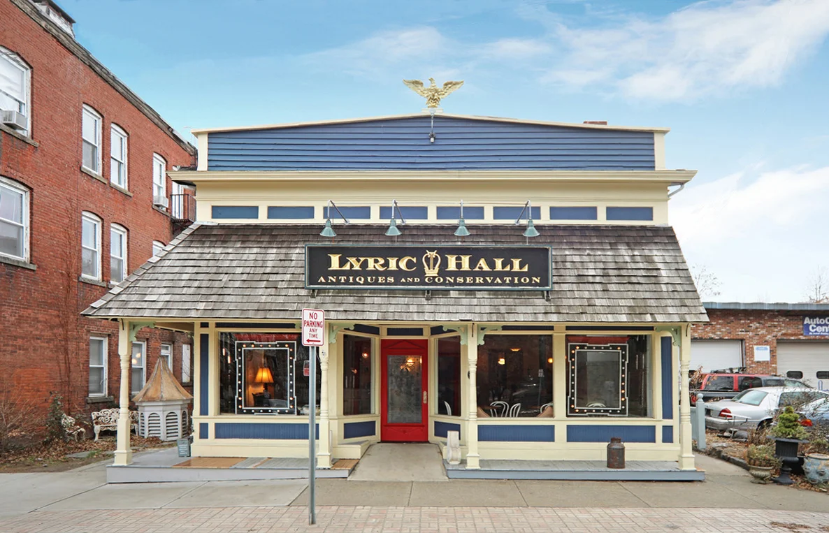2019 NHPT Merit Plaque Lyric Hall 827 Whalley Avenue Date: 1913 Owner: John Cavaliere In 2005, art conservationist John Cavaliere moved his antique restoration business known as Lyric Hall from State Street to Westville. At the time, 827 Whalley Avenue's architectural integrity was so altered that the original nomination of the Westville Village National Register Historic District in 2002 deliberately drew the boundary to exclude it. Closer examination of the structure revealed information regarding the building's original materials and its history as a short-lived theater, and initiated reconsideration. A consultant recommended by the New Haven Preservation Trust submitted a nomination to expand the boundary of Westville Village Historic District. What had been known as the Westville or West Rock Theater held historical and architectural significance consistent with that of the district to which it is immediately adjacent. From 2006–2010, Cavaliere renovated the property and turned it into Lyric Hall, an active community resource used as an antique gallery and performance space, consistent with its original historic function. Over the past decade, 827 Whalley Avenue has served as a visually striking gateway into the historic district, bringing the vitality and character of the past into today’s vibrant Westville Village. Photo: Jamie Cuzzocreo, H Pearce Commercial Real Estate