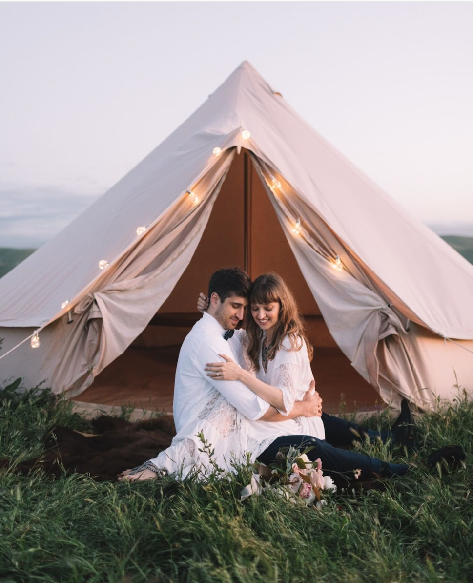 Stout Tent as backdrop of scene, Christmas lights OR bistro lights strung around perimeter of tent and entrance.