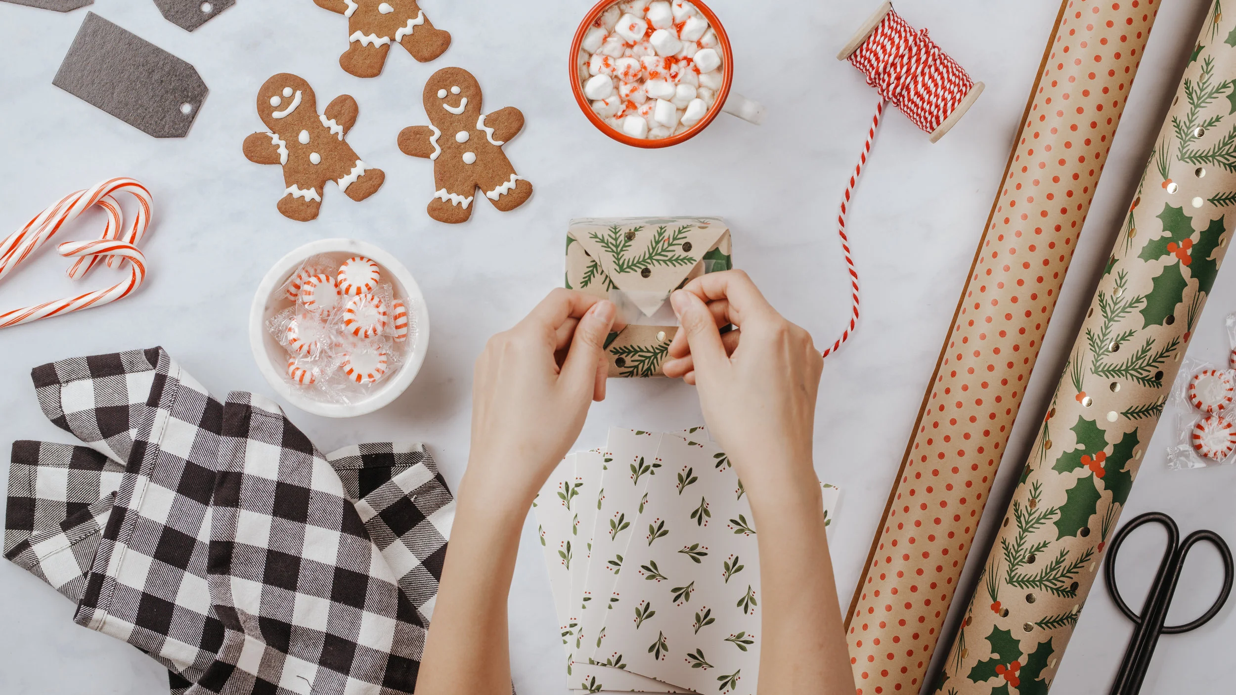 Gift-giving flatlay (flatlay layout will be customized to the Woods Christmas set - items like a plate of peppermint cookies, 2 mugs of cocoa, candy canes, mittens, ornaments, greenery, etc. will be featured.)