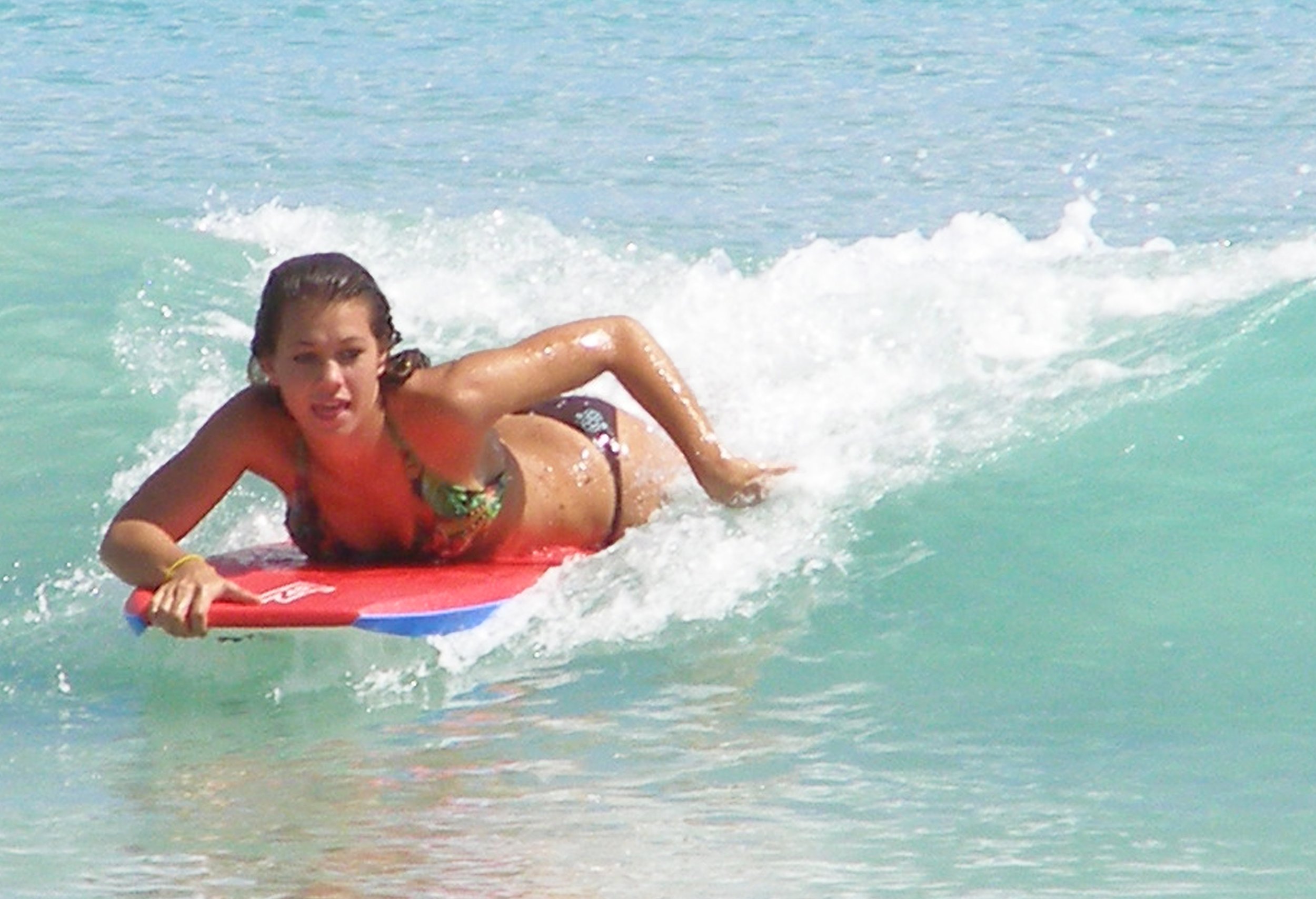 A young girl in a swimsuit riding a surfboard on the ocean waves.
