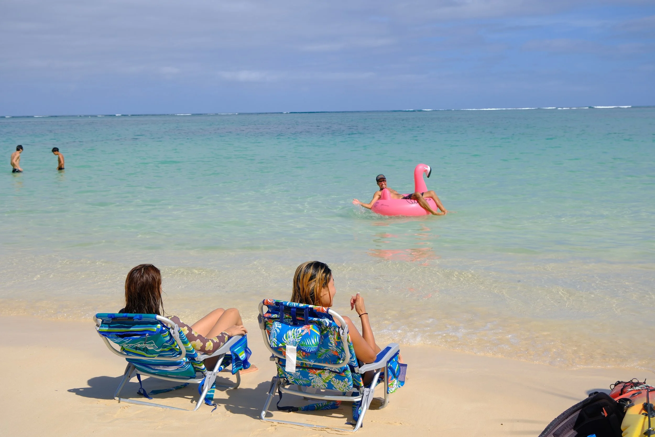 Tropical beach with turquoise water, palm trees, blue sky, and small islands in the background.
