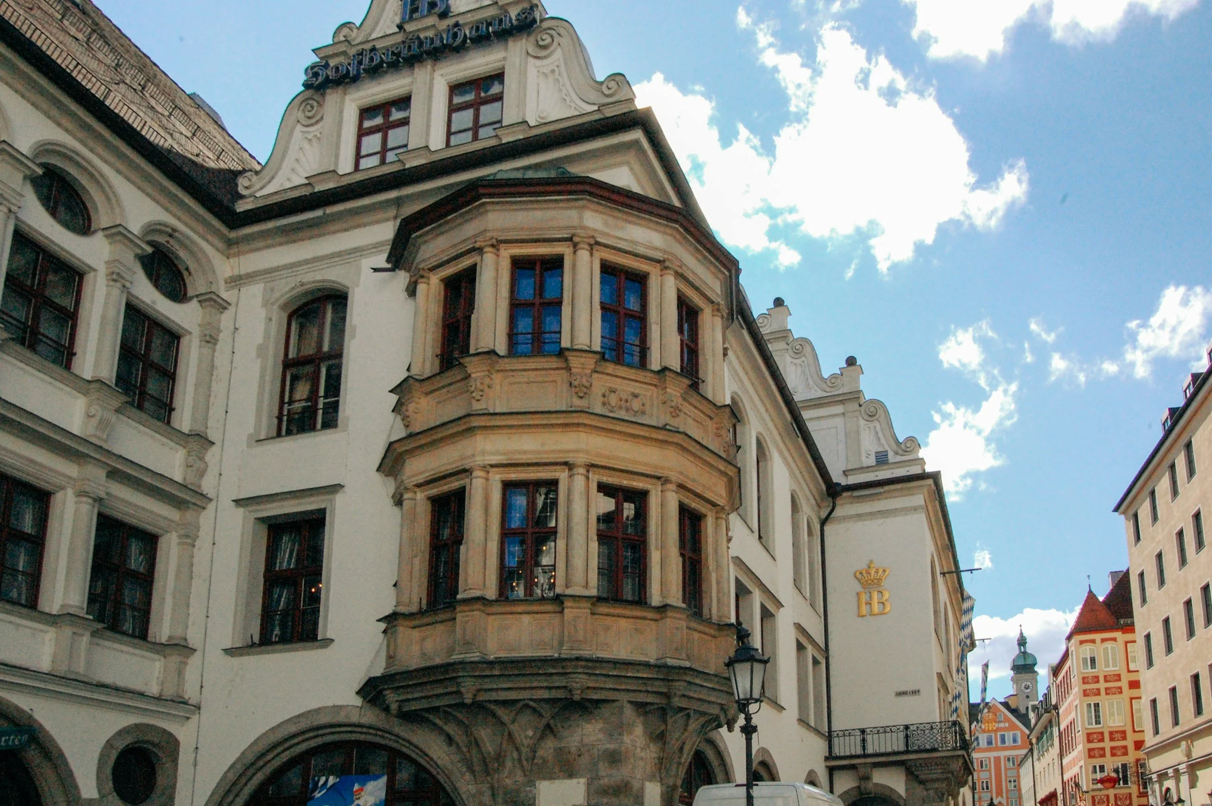 Historical building with ornate architecture and multiple windows, with a blue sky and clouds in the background.