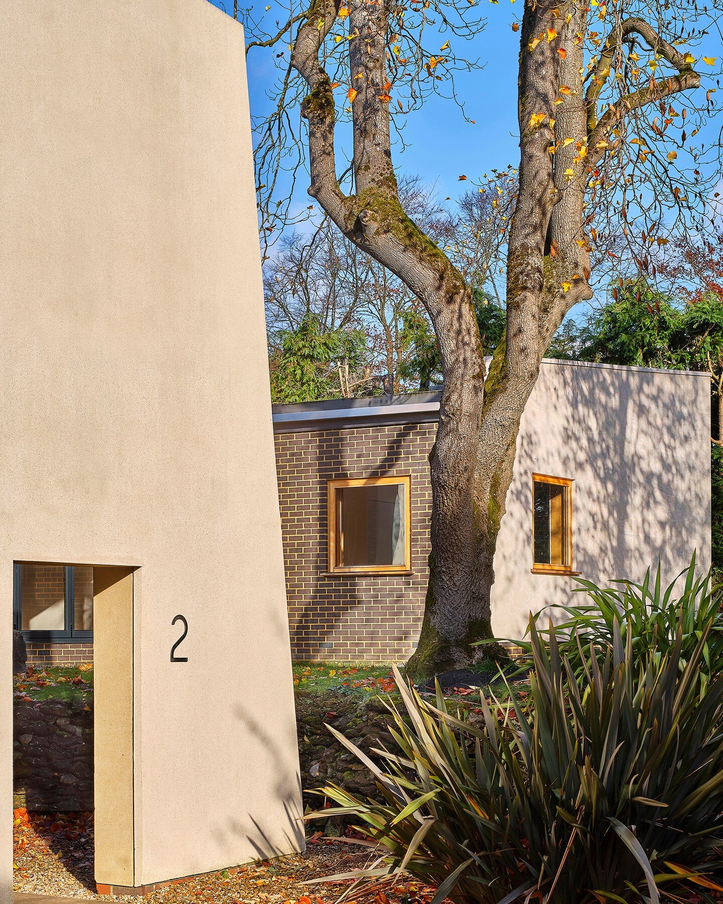 In contrast to the large matt render end walls of the existing building, the new extension is clad in high-gloss tiles, which reflect both daylight and the gardens that surround the house. 

Our proposals extended this house in Surrey, by architect G