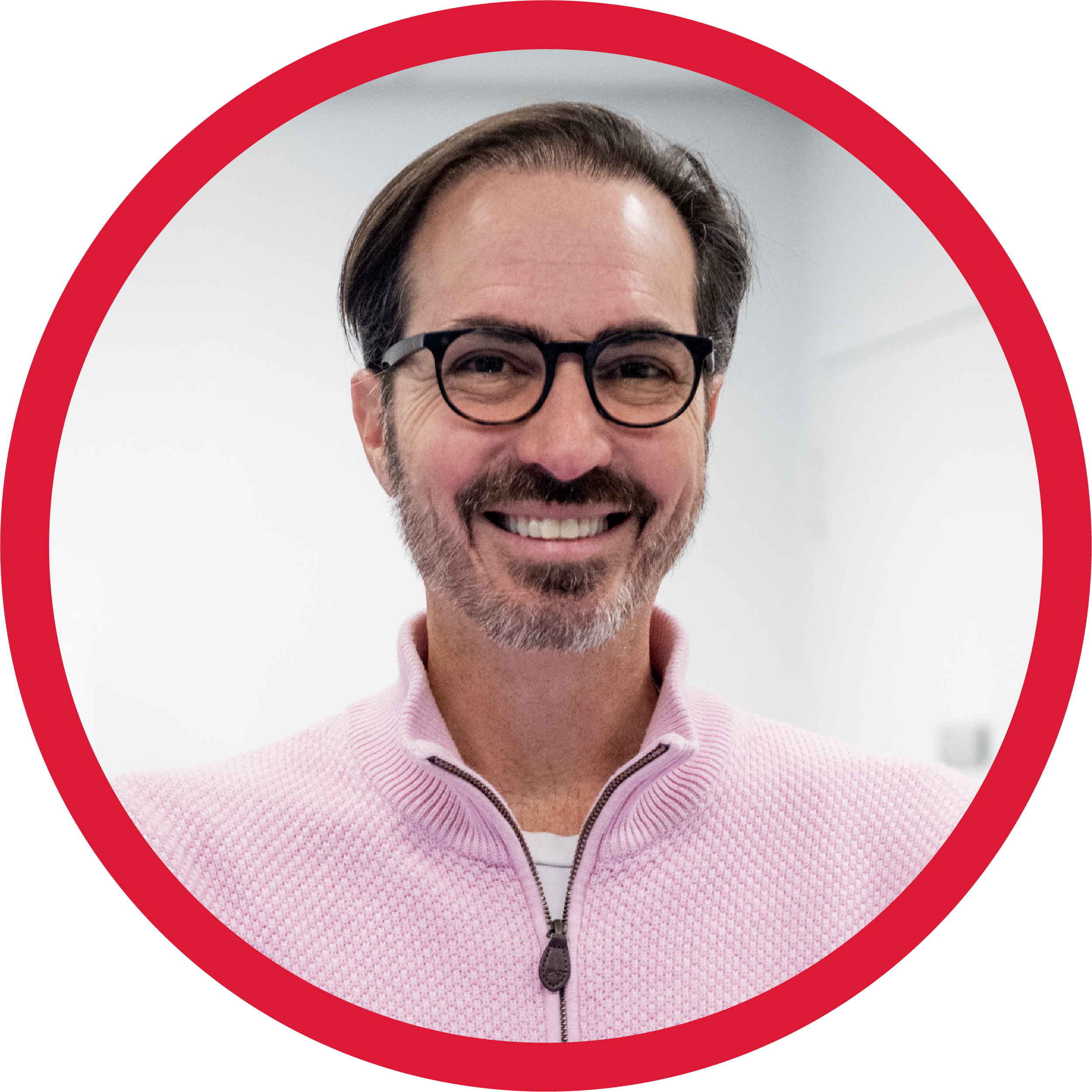 Smiling middle-aged man with glasses and beard wearing a pink zip-up sweater.