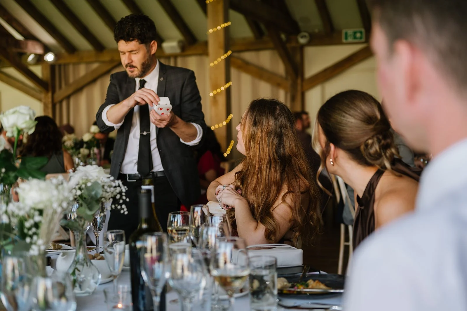 Magician entertaining guests at barn wedding reception