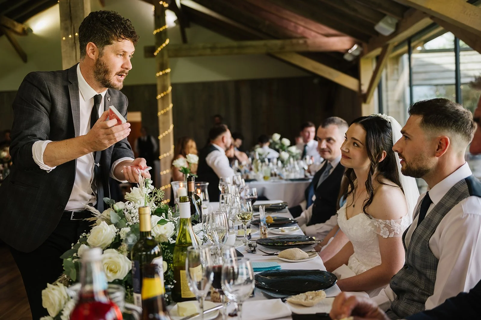 Magician entertaining guests at barn wedding reception