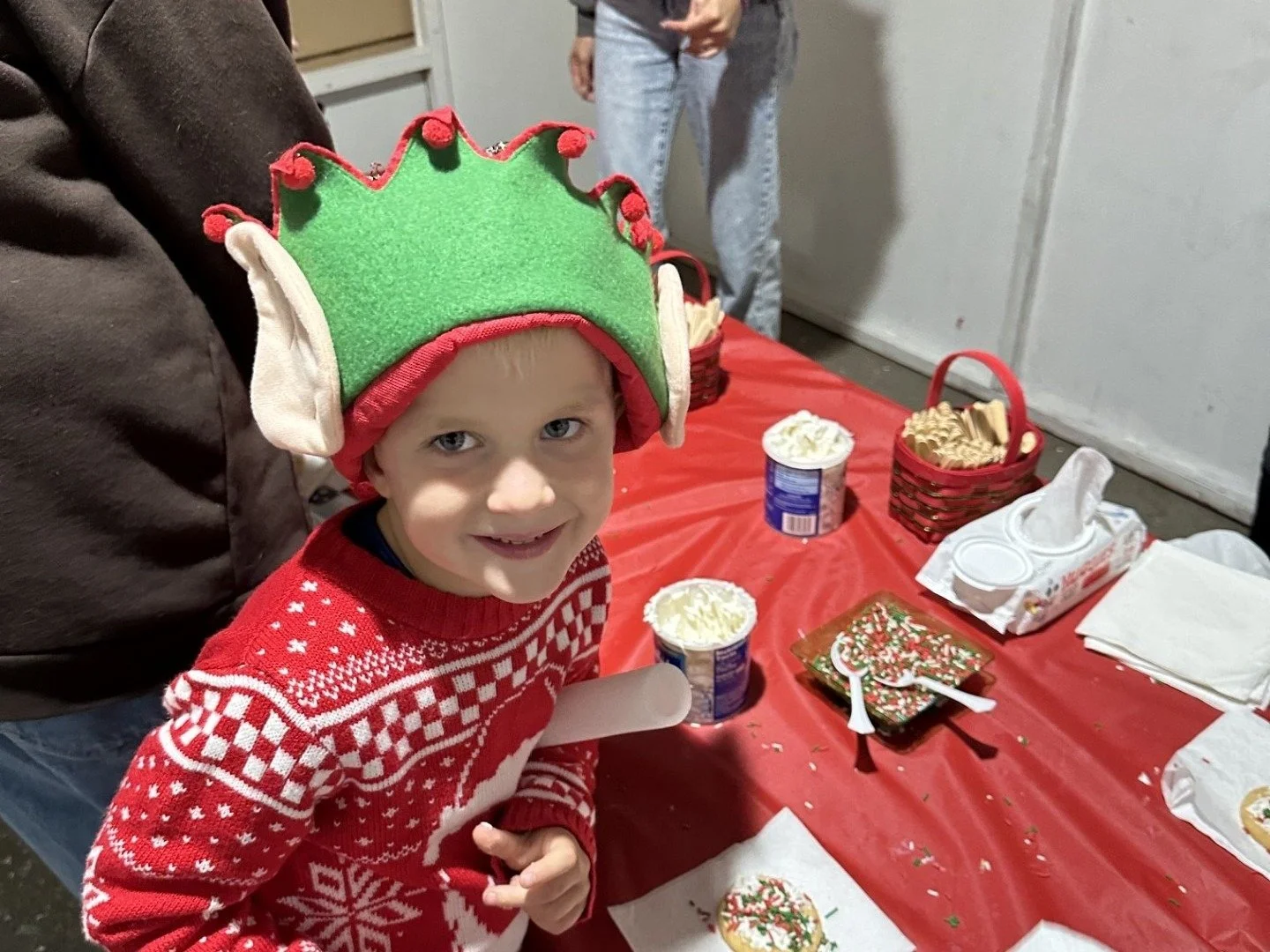 A boy in an elf hat decorating a Christmas cookie at The Hills