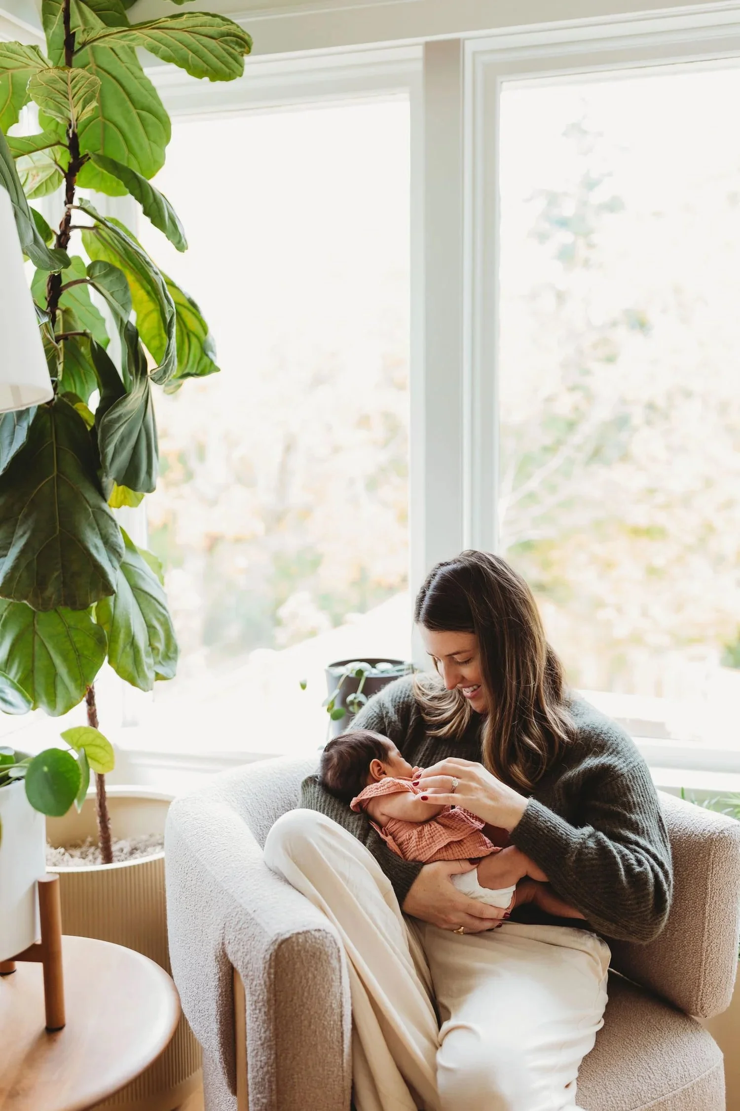 Mom holding newborn in natural light by window during lifestyle newborn photo session in Seattle