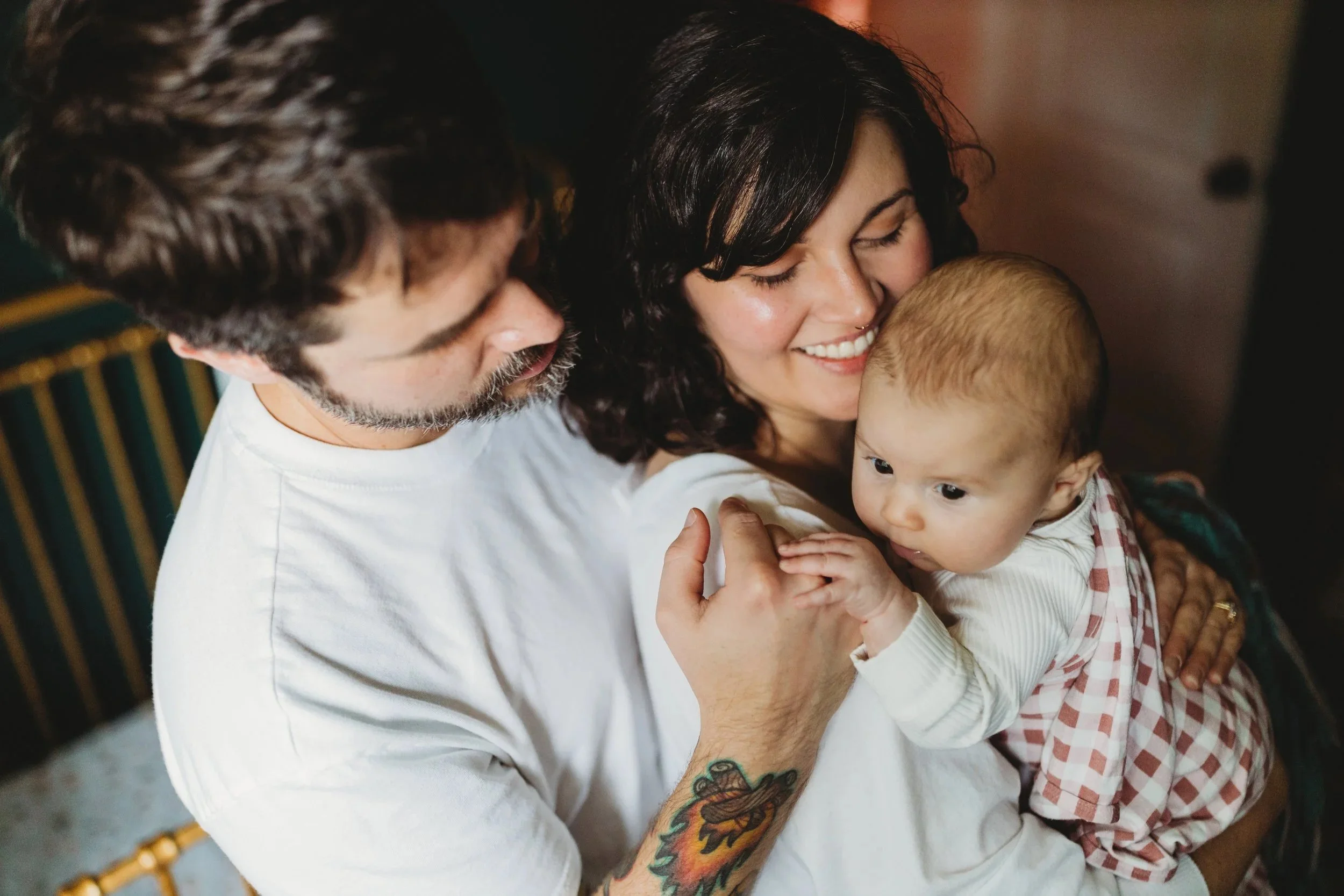 Parents smiling at wide-eyed newborn during lifestyle newborn photo session at home in Seattle