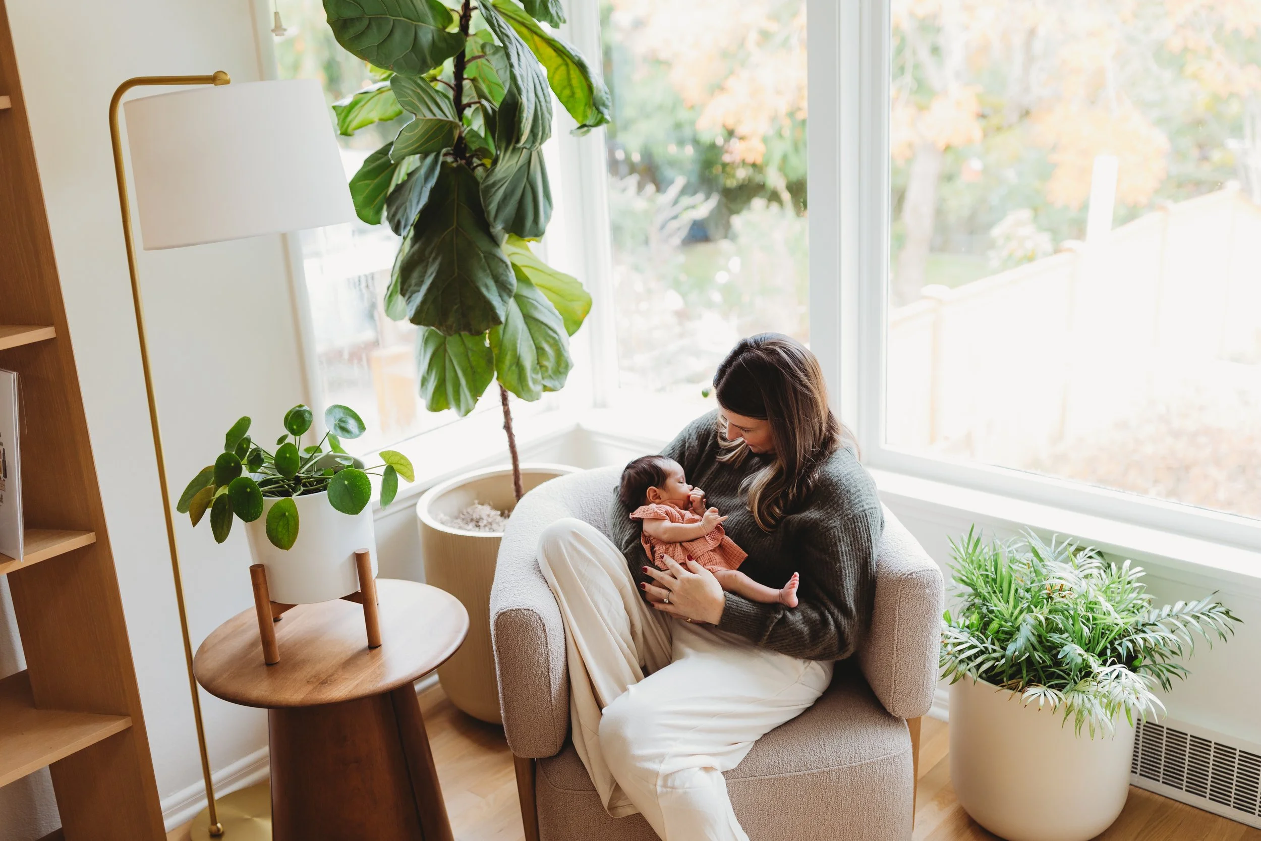 Mother holding her newborn in a cozy Seattle home, showing the relaxed, natural style of an in-home lifestyle newborn photo session.