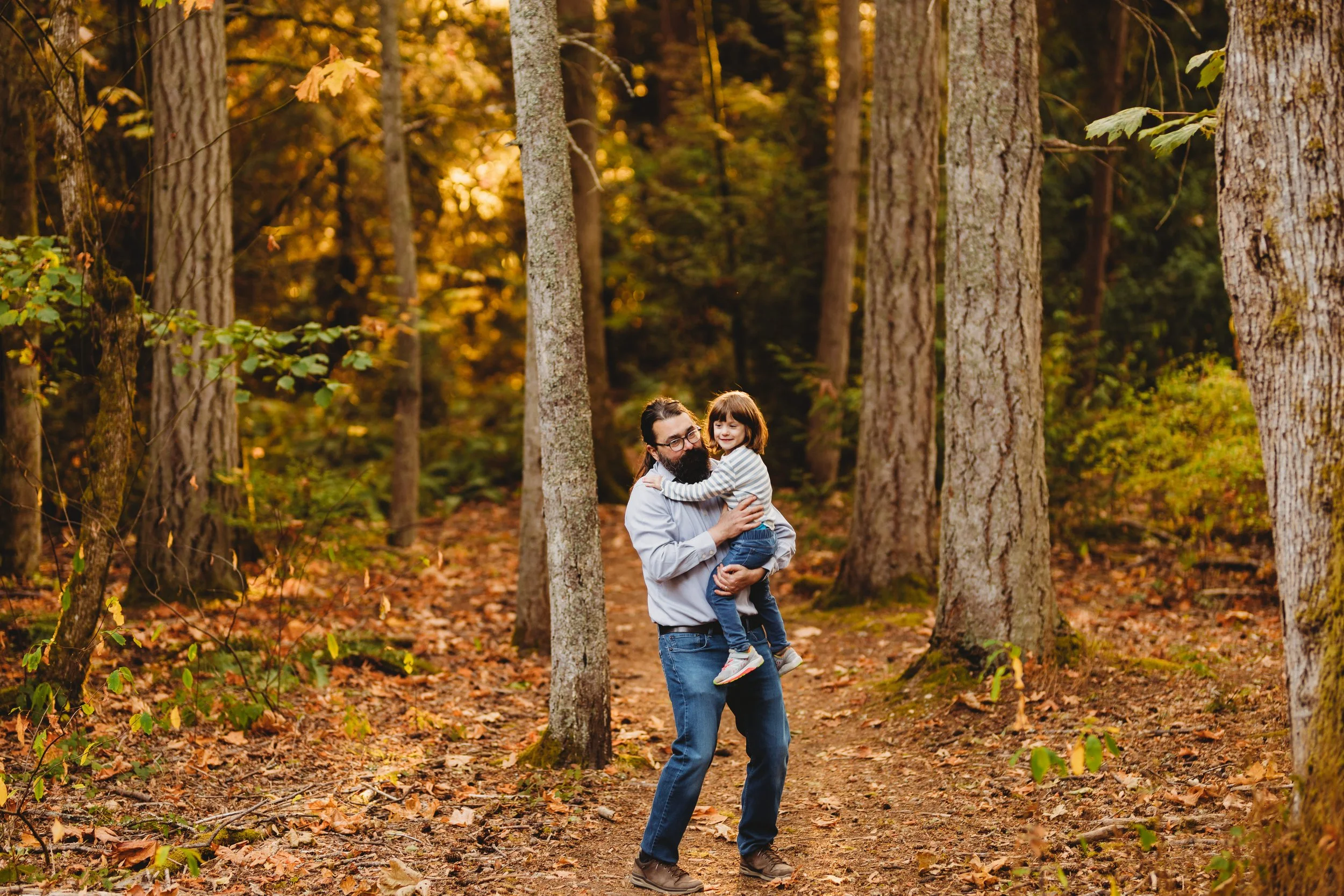 Father holding his child on a wooded trail at Boeing Creek Park during a relaxed natural light family photo session.