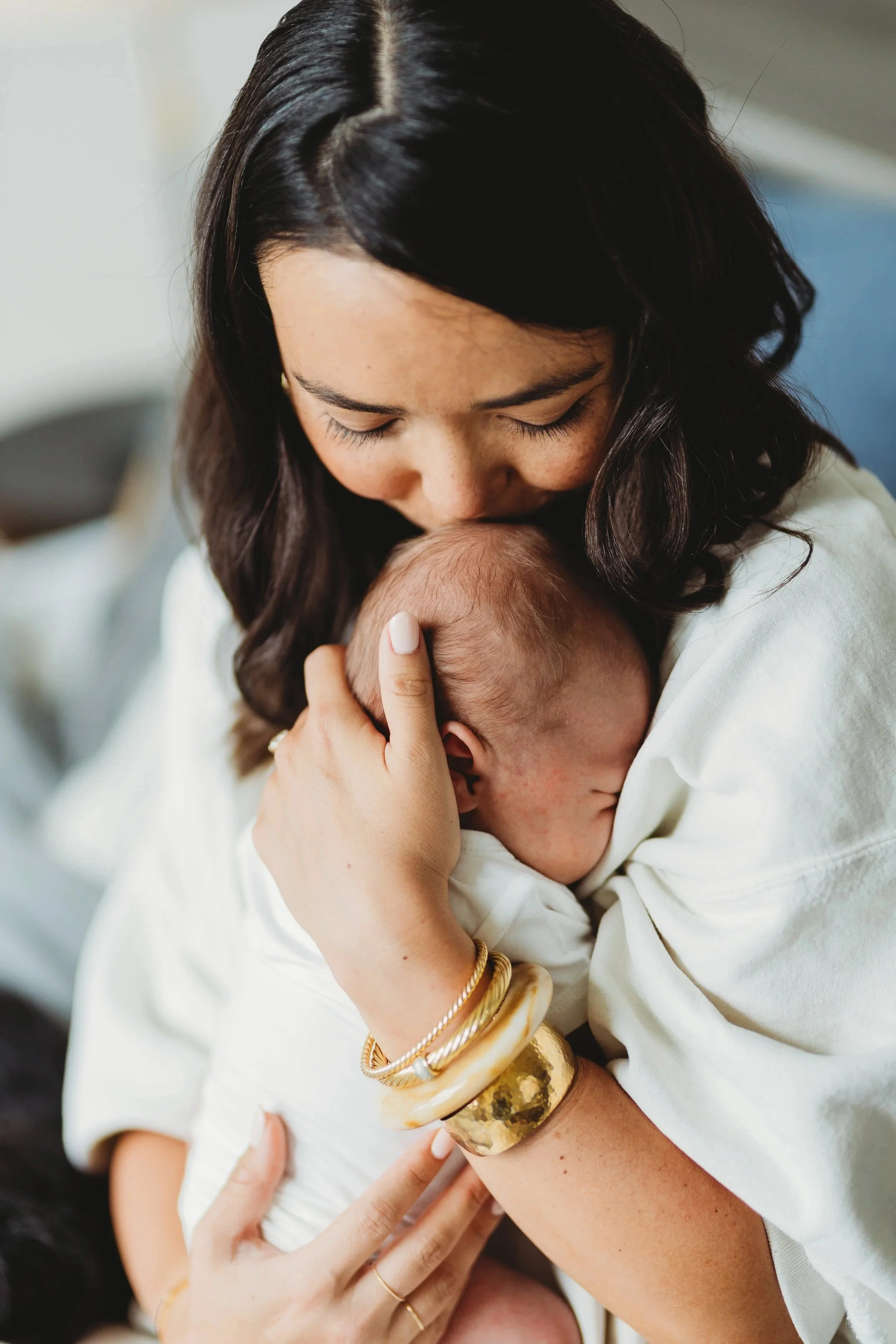 Parent gently kissing their newborn during an in-home lifestyle newborn photography session in Seattle.