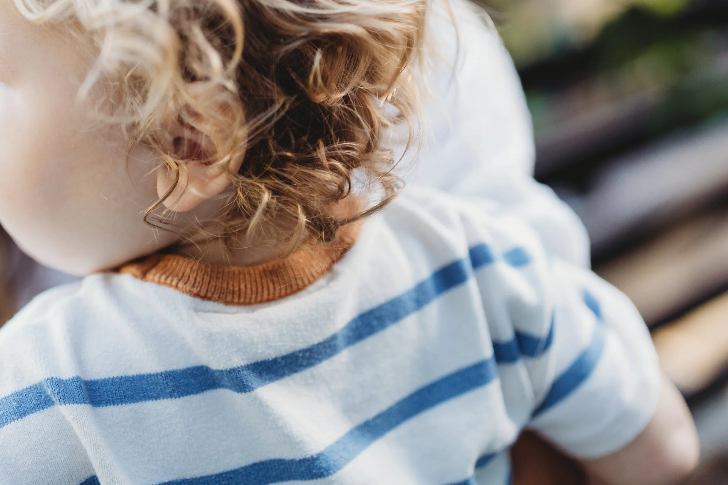 Close-up detail of a toddler's curly blonde hair glowing in warm afternoon light — Seattle lifestyle family photography