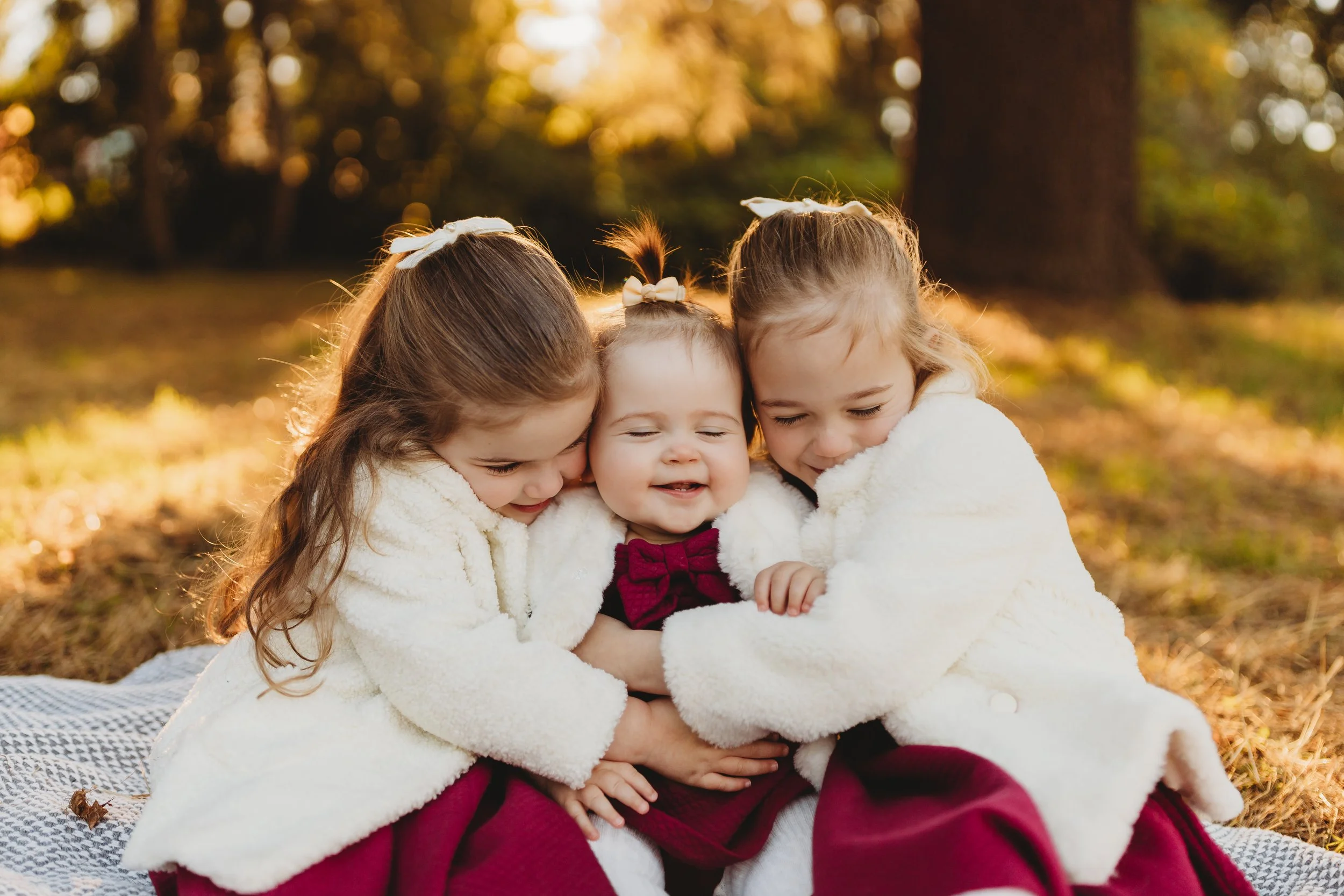 Three sisters snuggled together in matching cream jackets, Juanita Bay Park fall mini session, Seattle photographer
