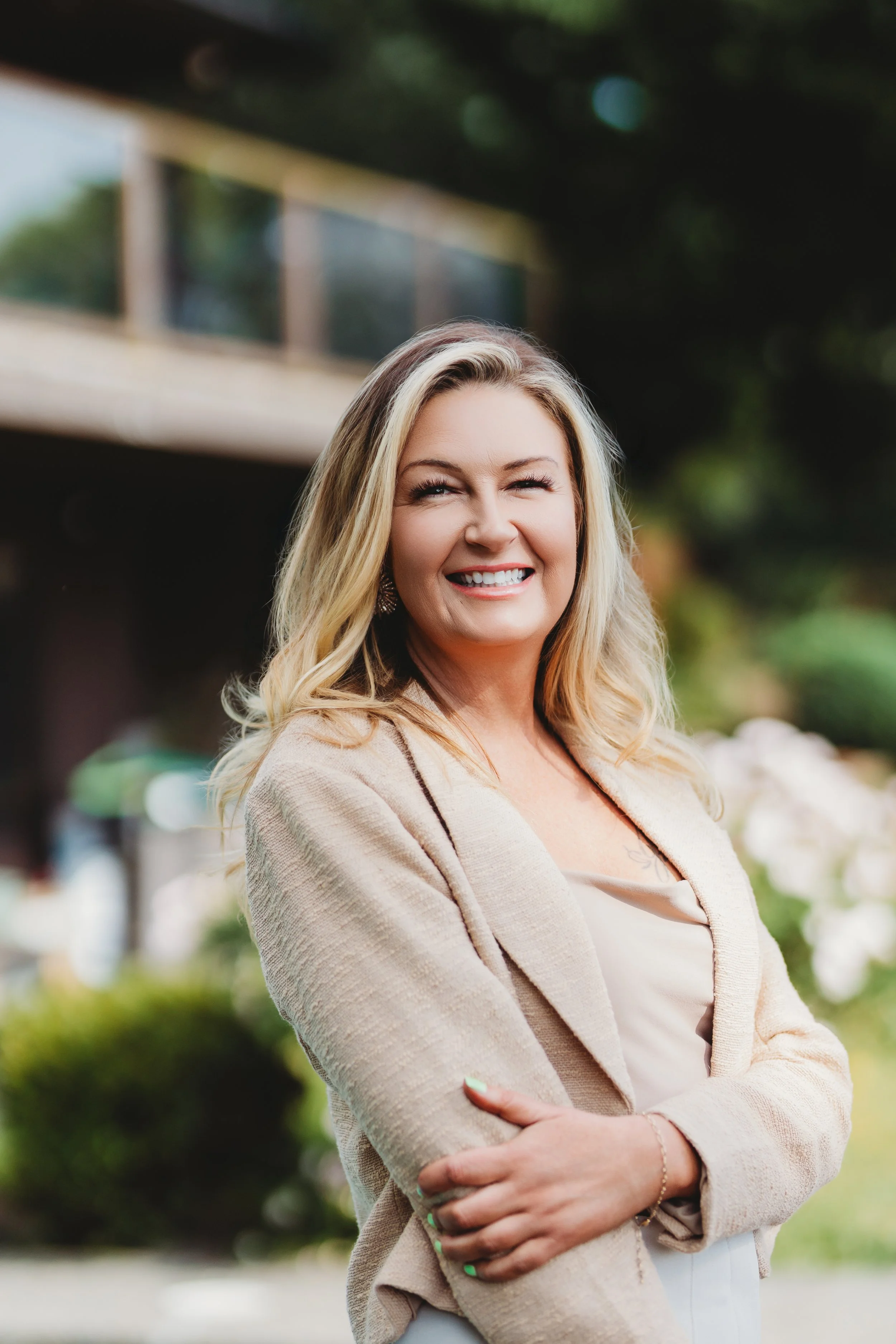 A natural-light professional headshot of a real estate agent photographed in West Seattle, featuring a relaxed, well-fitting outfit that allows for comfortable movement and a confident, approachable presence.