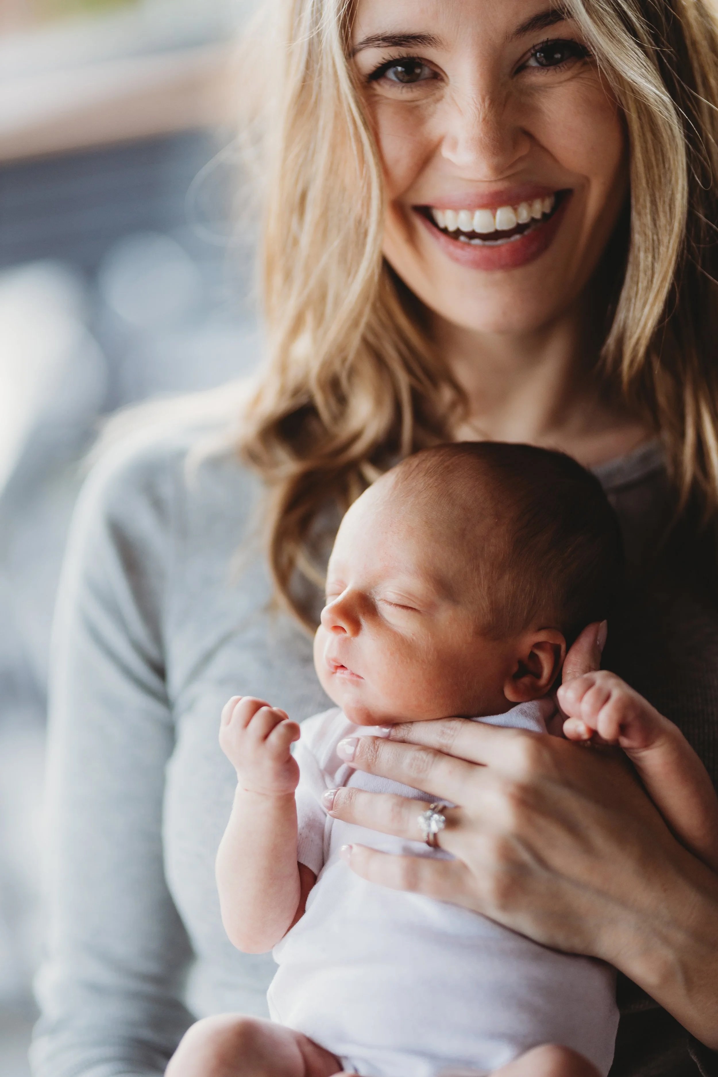Mom laughing while holding newborn during lifestyle newborn photo session in Seattle