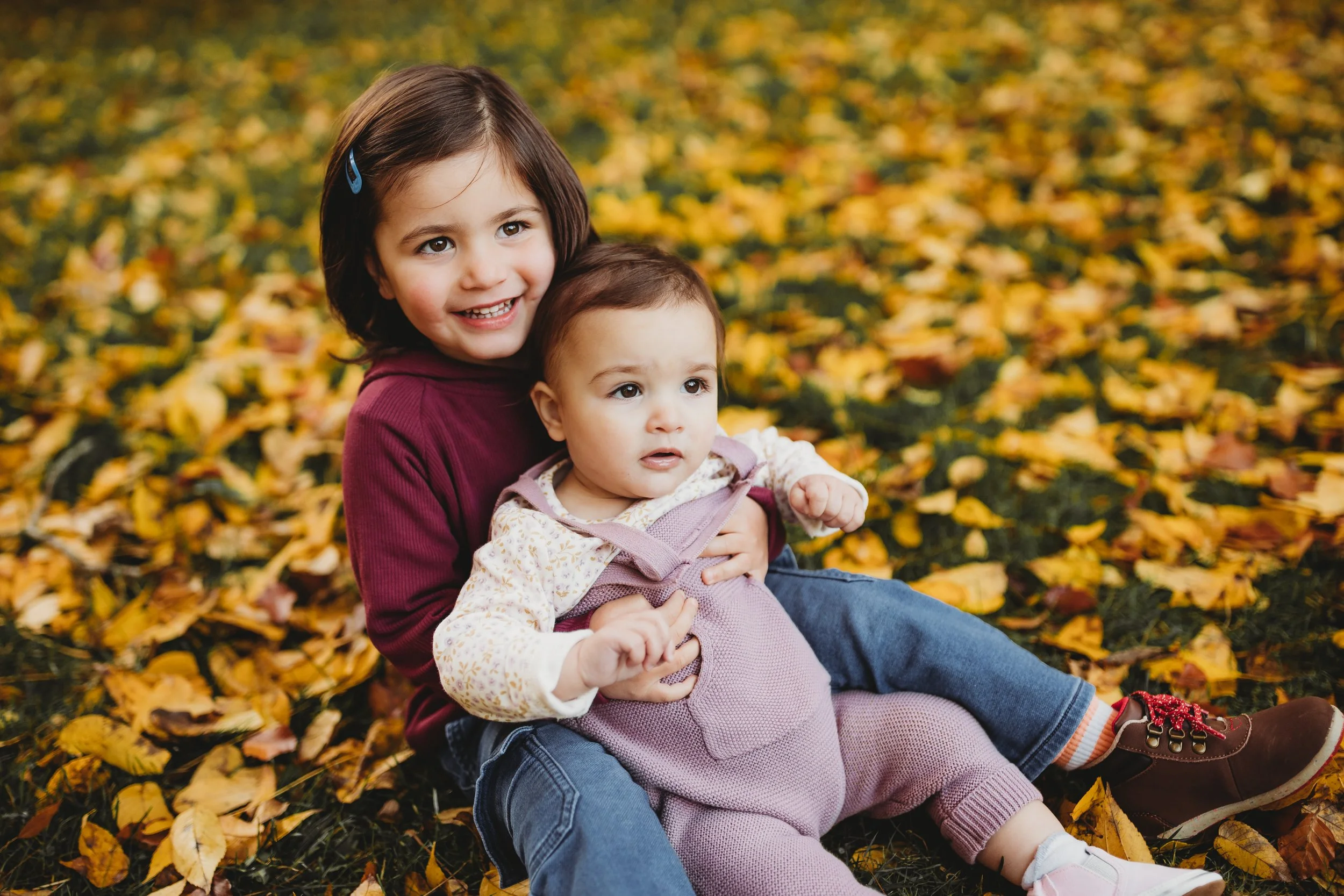 Older sibling holding a baby during a calm and connected family photo session