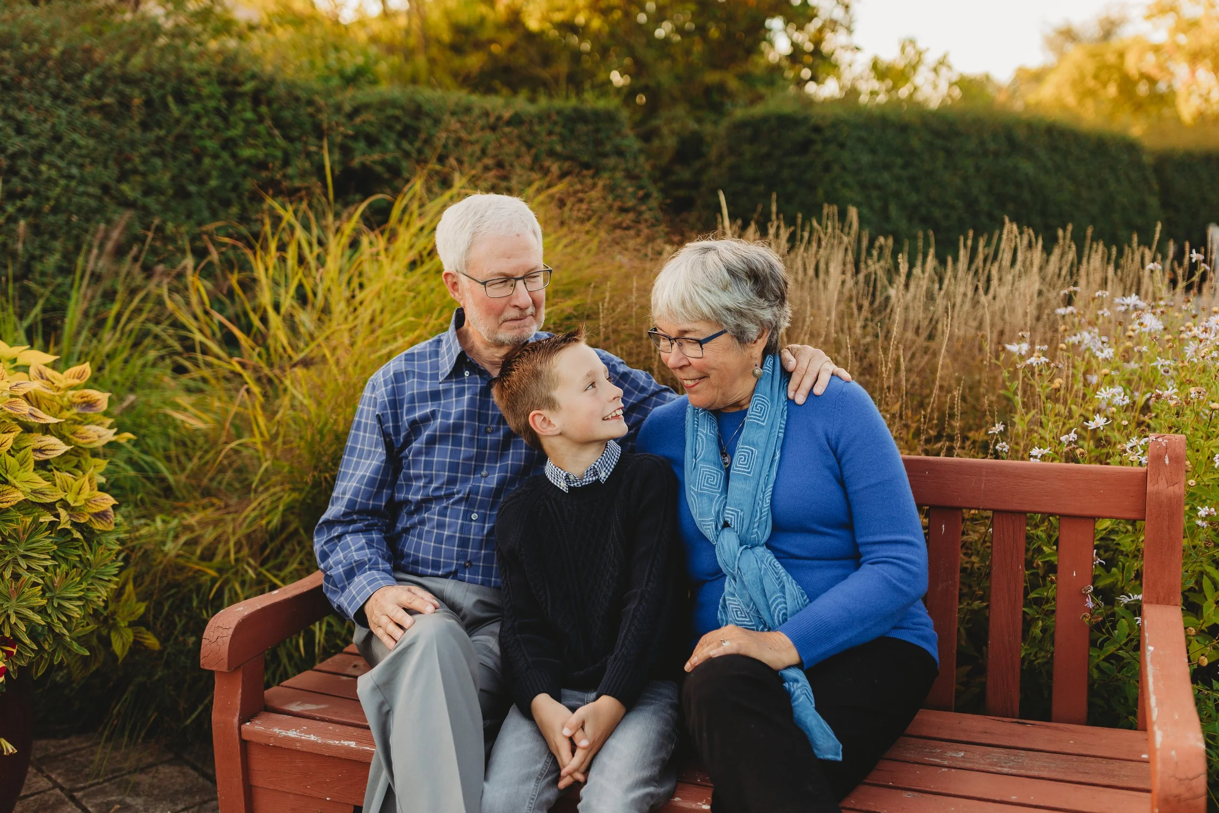 Grandparents sitting with their grandson on a garden bench during a family photo session at the Center for Urban Horticulture in Seattle