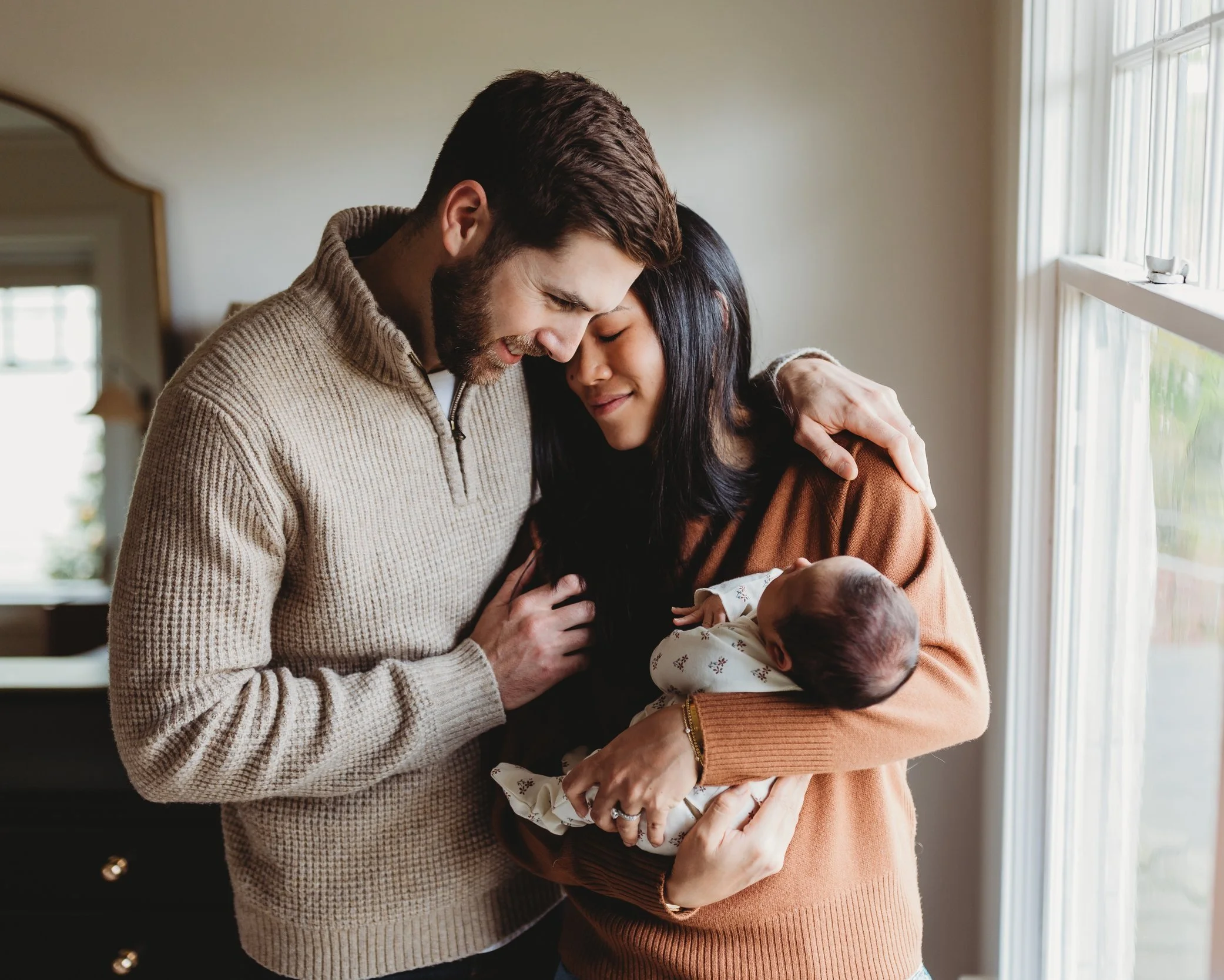 Parents holding their newborn during an in-home newborn photo session in Seattle with natural window light