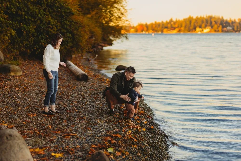 Family spending time together by the water during a natural light family photo session at Luther Burbank Park on Mercer Island.