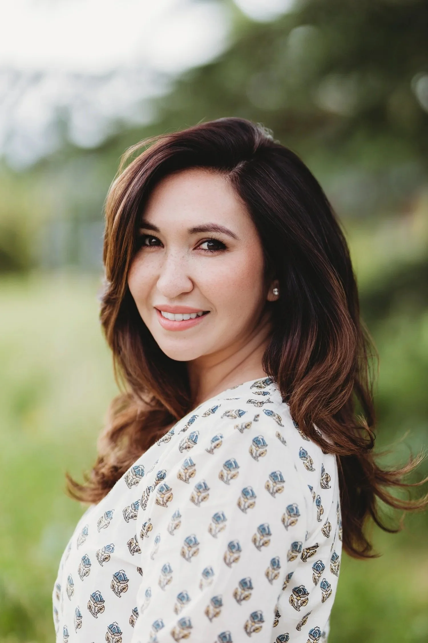 A natural-light professional headshot photographed outdoors in Seattle, featuring a soft, subtle pattern that adds interest without distracting from the face.