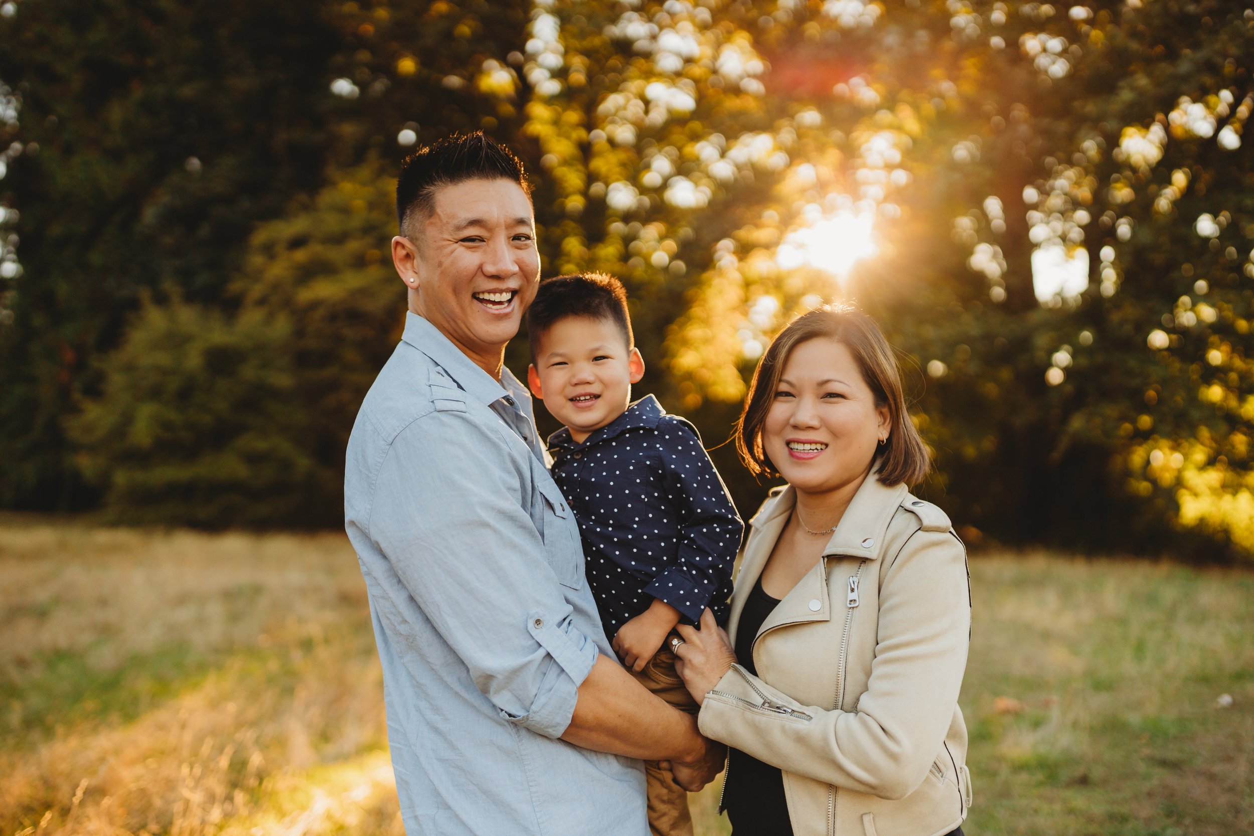 Family of three smiling together at golden hour, Juanita Bay Park fall mini session, Seattle photographer