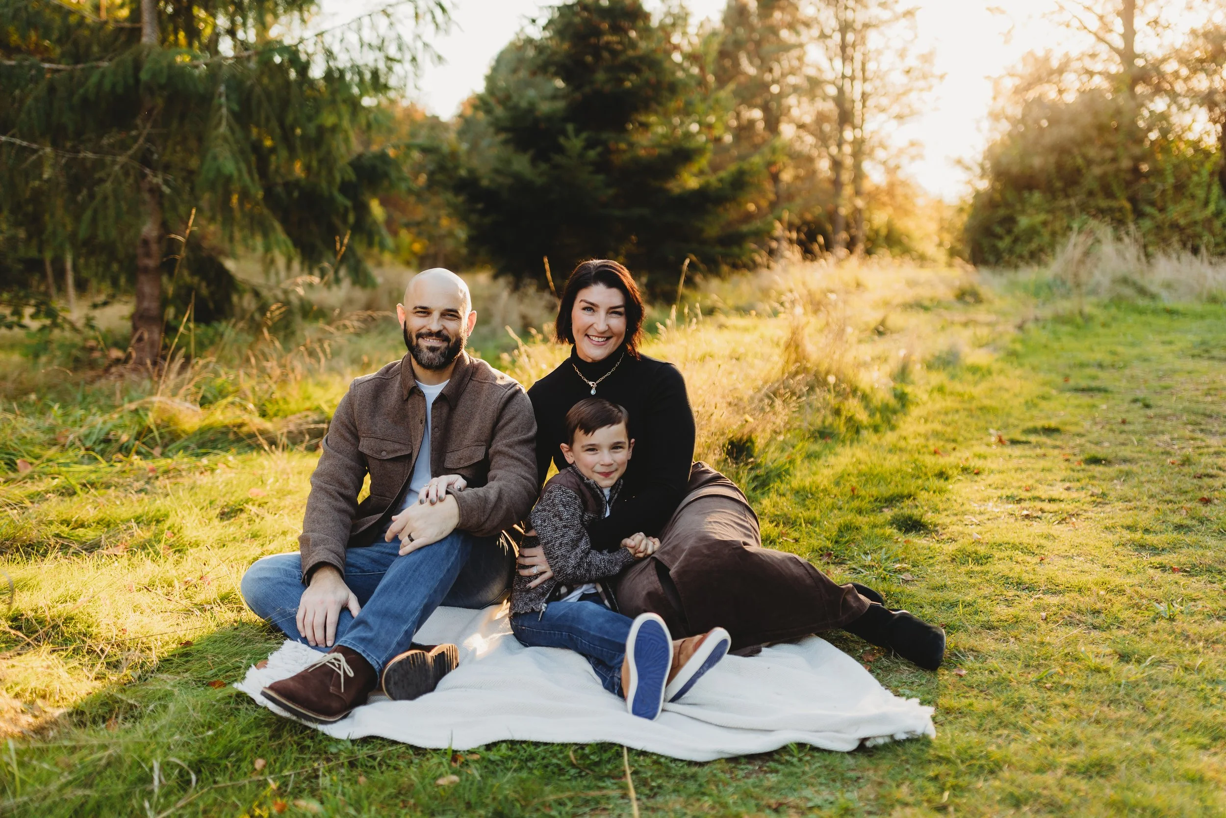 Family sitting together on a blanket at Discovery Park in Seattle during a relaxed natural light family photo session.