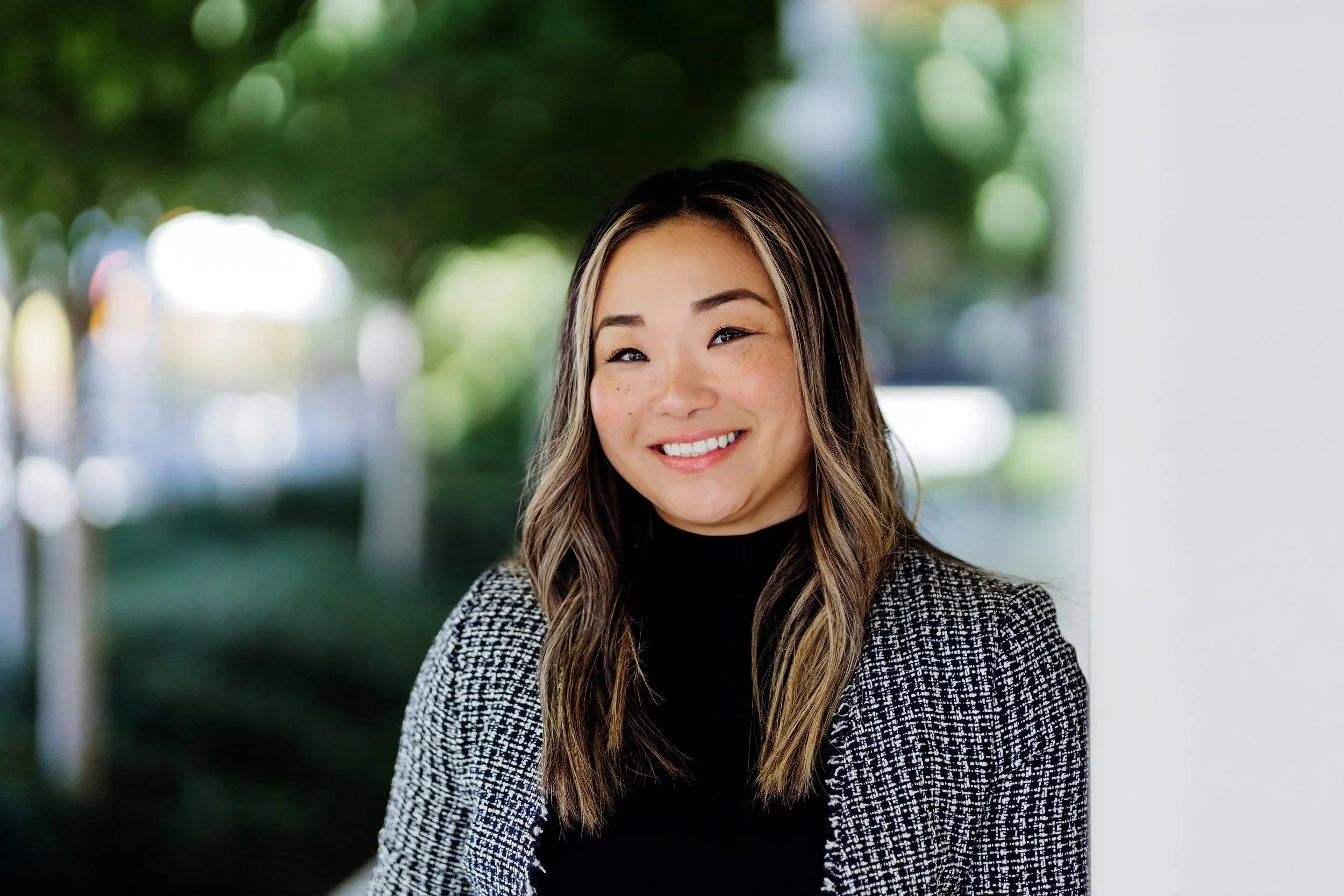 Professional headshot taken outdoors at University Village in Seattle, featuring natural light and a relaxed, approachable style.