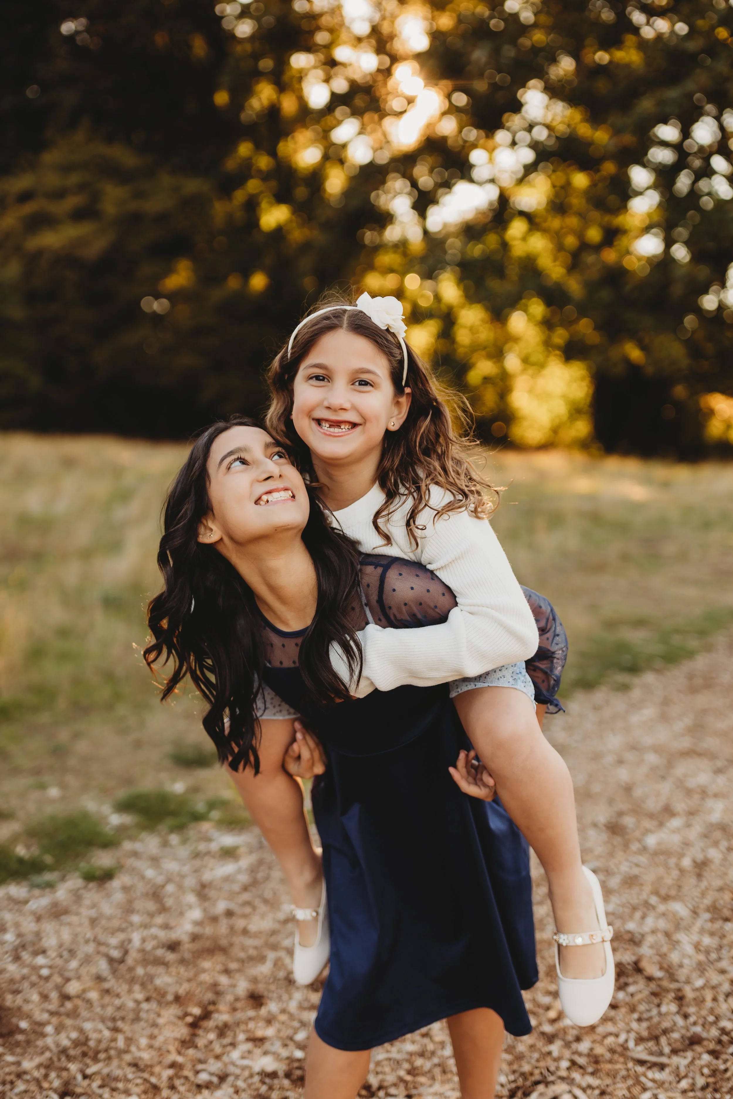Two sisters laughing during a piggyback ride at golden hour, Juanita Bay Park fall mini session, Seattle photographer