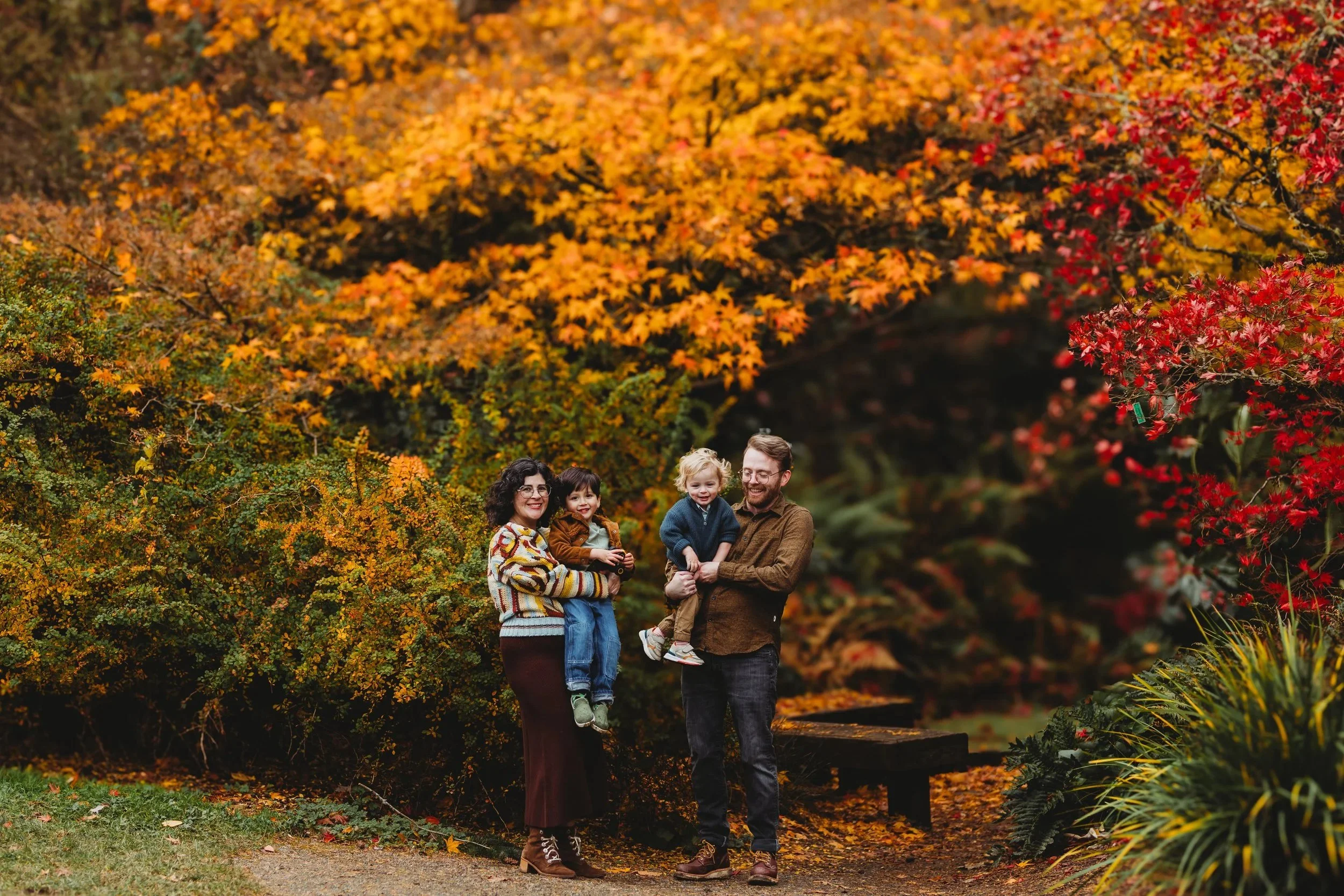 Family standing together among fall foliage during a natural light family photo session at the Washington Park Arboretum in Seattle.