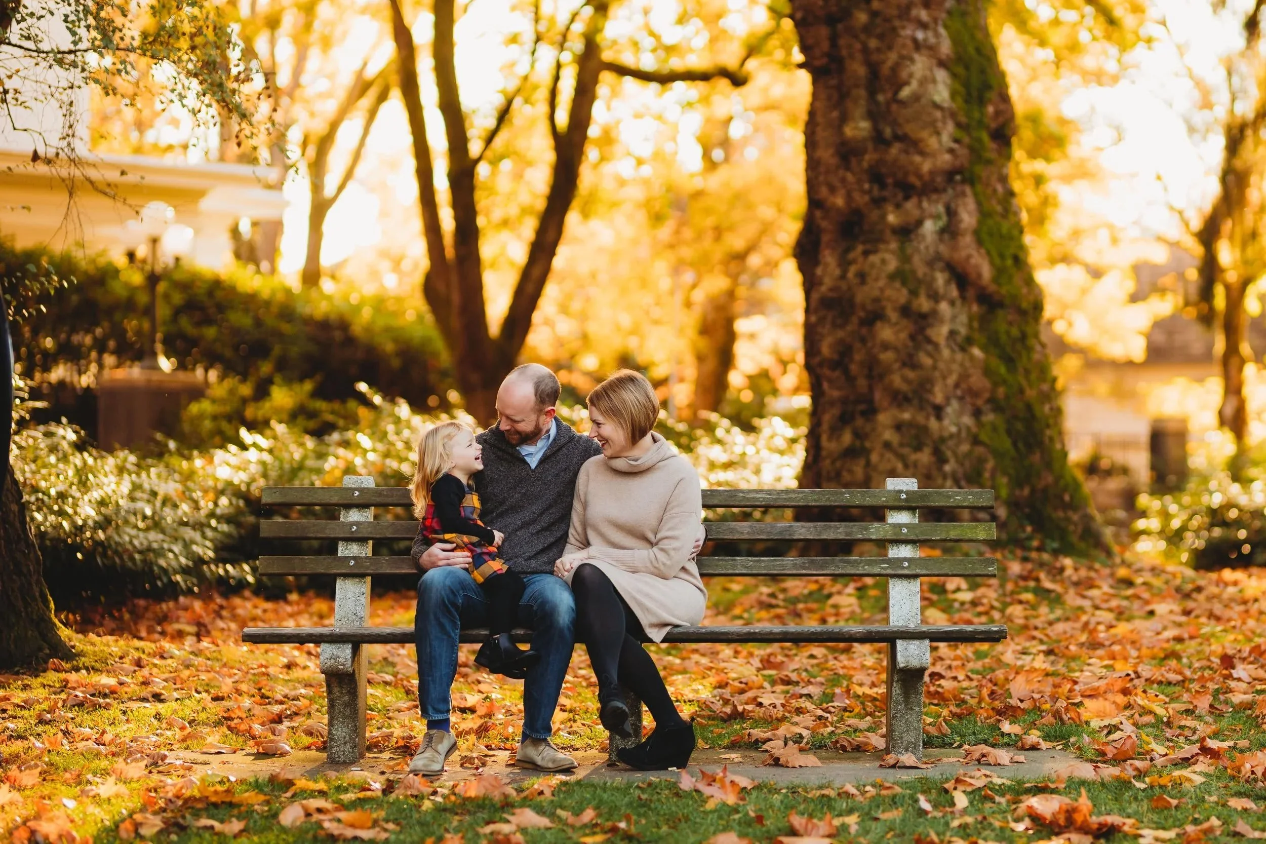 Family sitting together on a park bench during a fall family photo session at Volunteer Park in Seattle