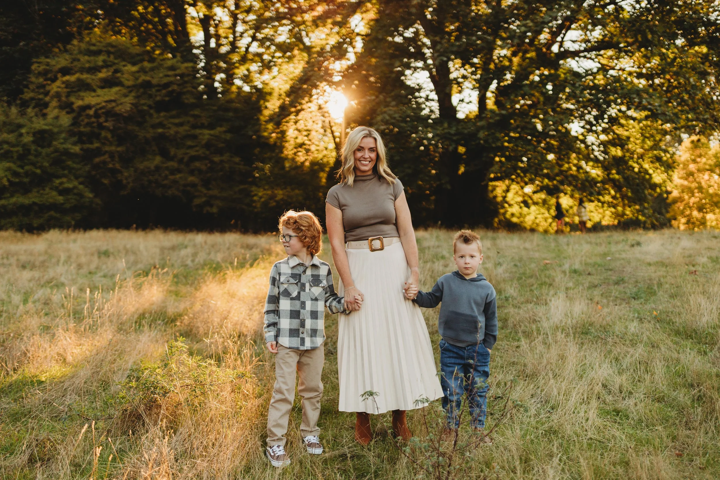 Mom holding hands with her two sons in a golden field, Juanita Bay Park fall mini session, Seattle photographer