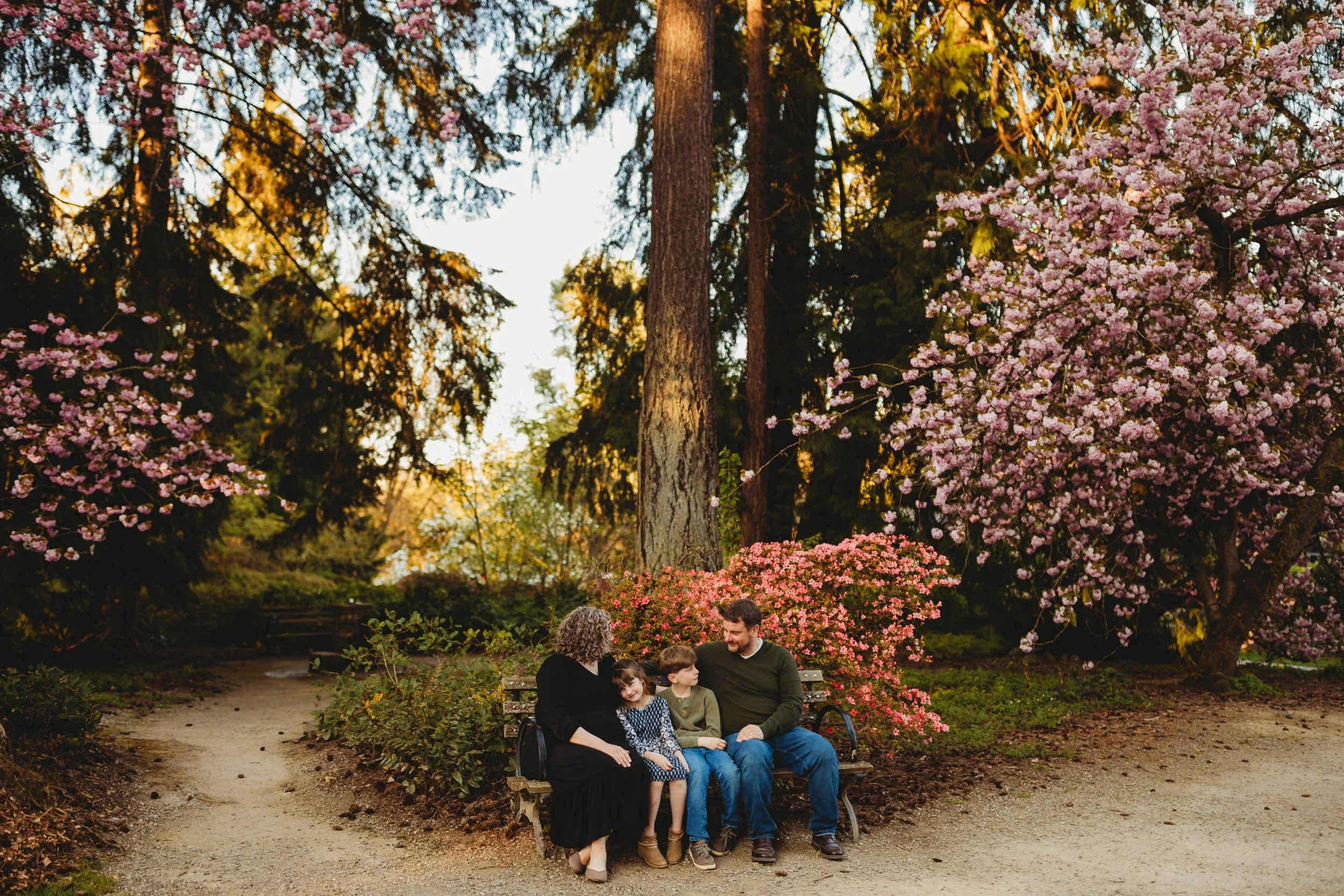 Family sitting together on a bench surrounded by spring blooms during a natural light family photo session at the Washington Park Arboretum in Seattle.