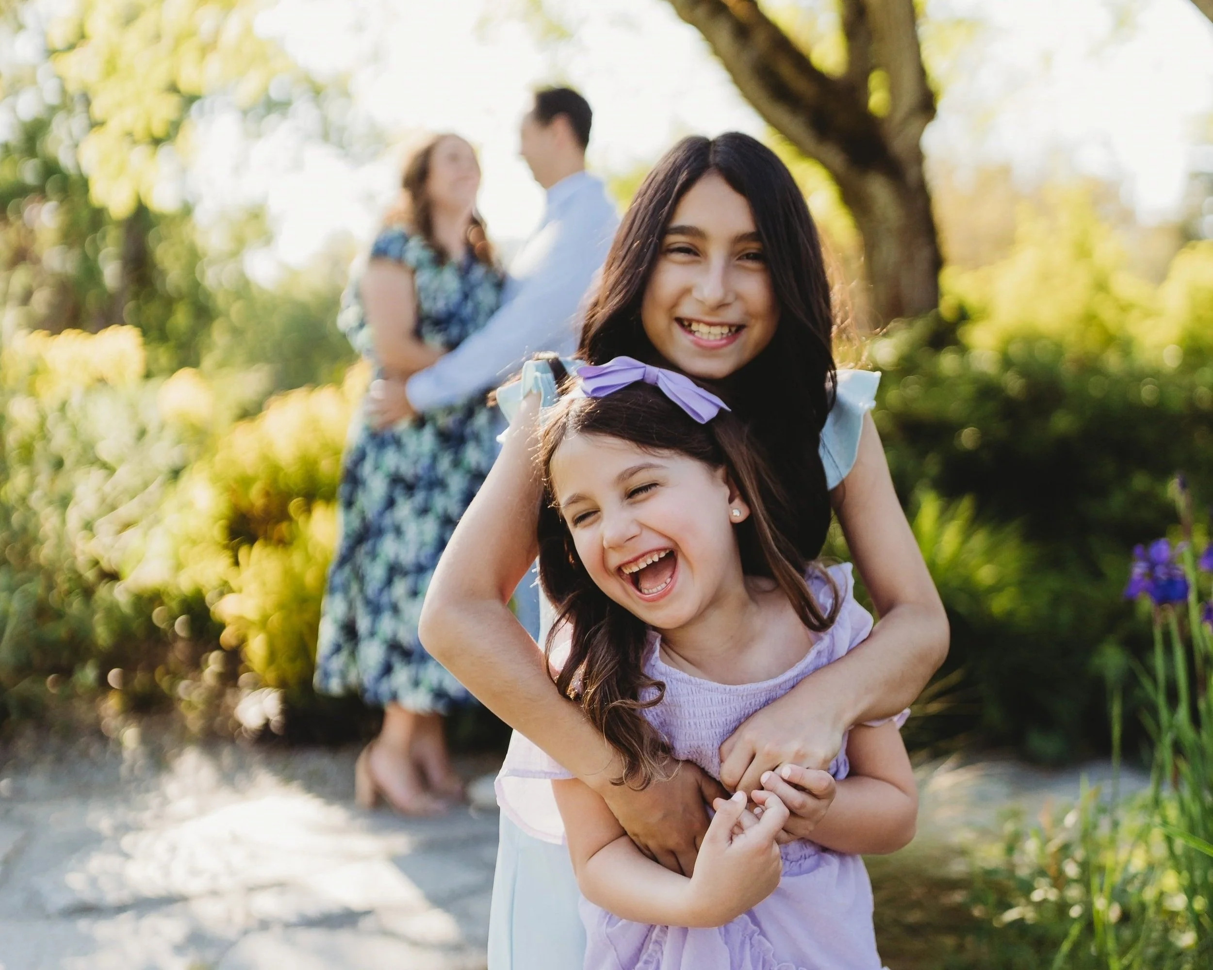 Sisters laughing together during a family photo session at Bellevue Botanical Garden near Seattle