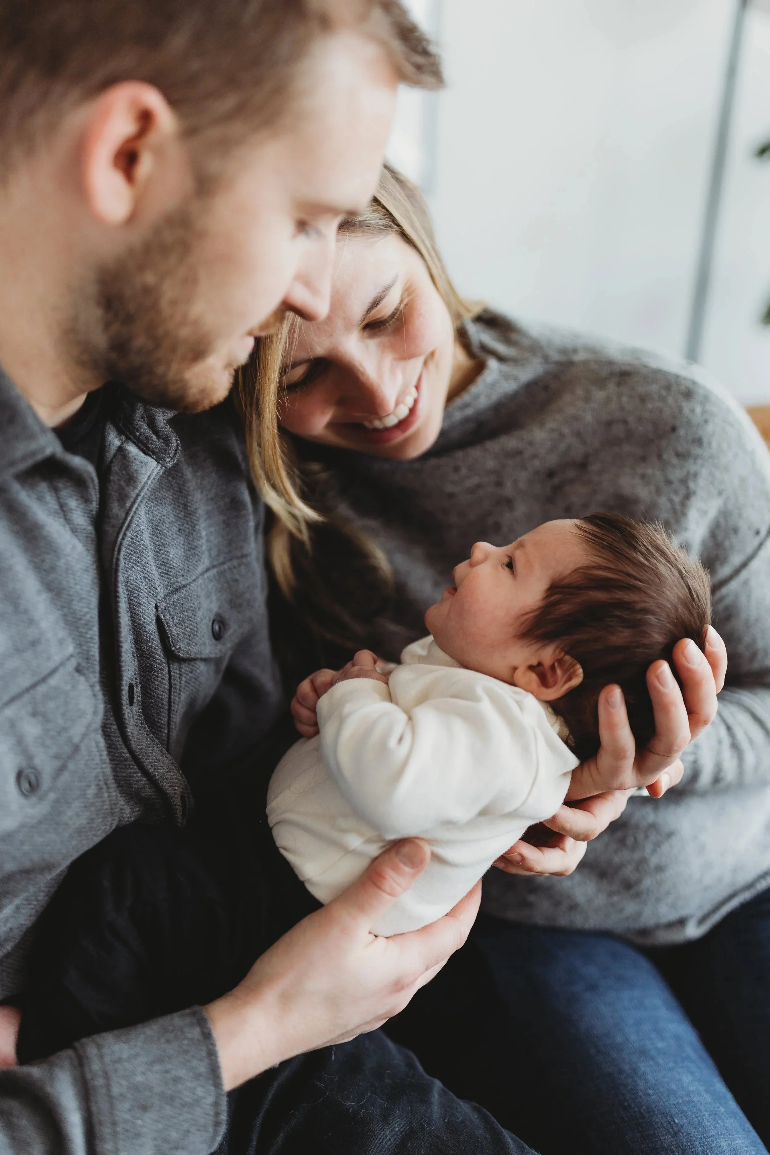 Parents holding and gazing at their newborn during a calm, in-home lifestyle newborn photo session in Seattle.