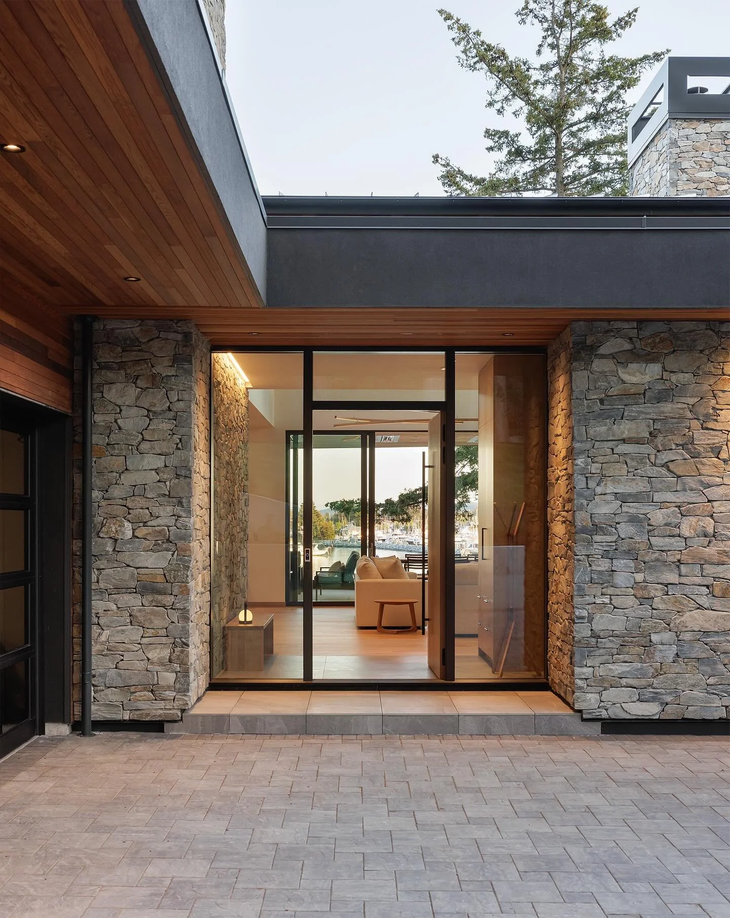 There is nothing like coming home. 
.
This entryway immediately captures the essence of the home, offering a vista of the water beyond from the moment one steps inside. The connection between interior and exterior is emphasized by the use of stone cl