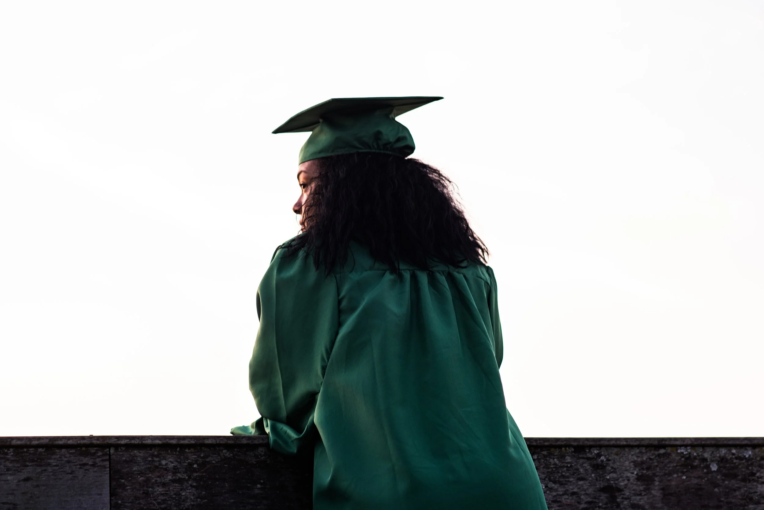 Image: Young woman in a graduation cap looking over ledge. Photo: Photo by Andre Hunter on Unsplash