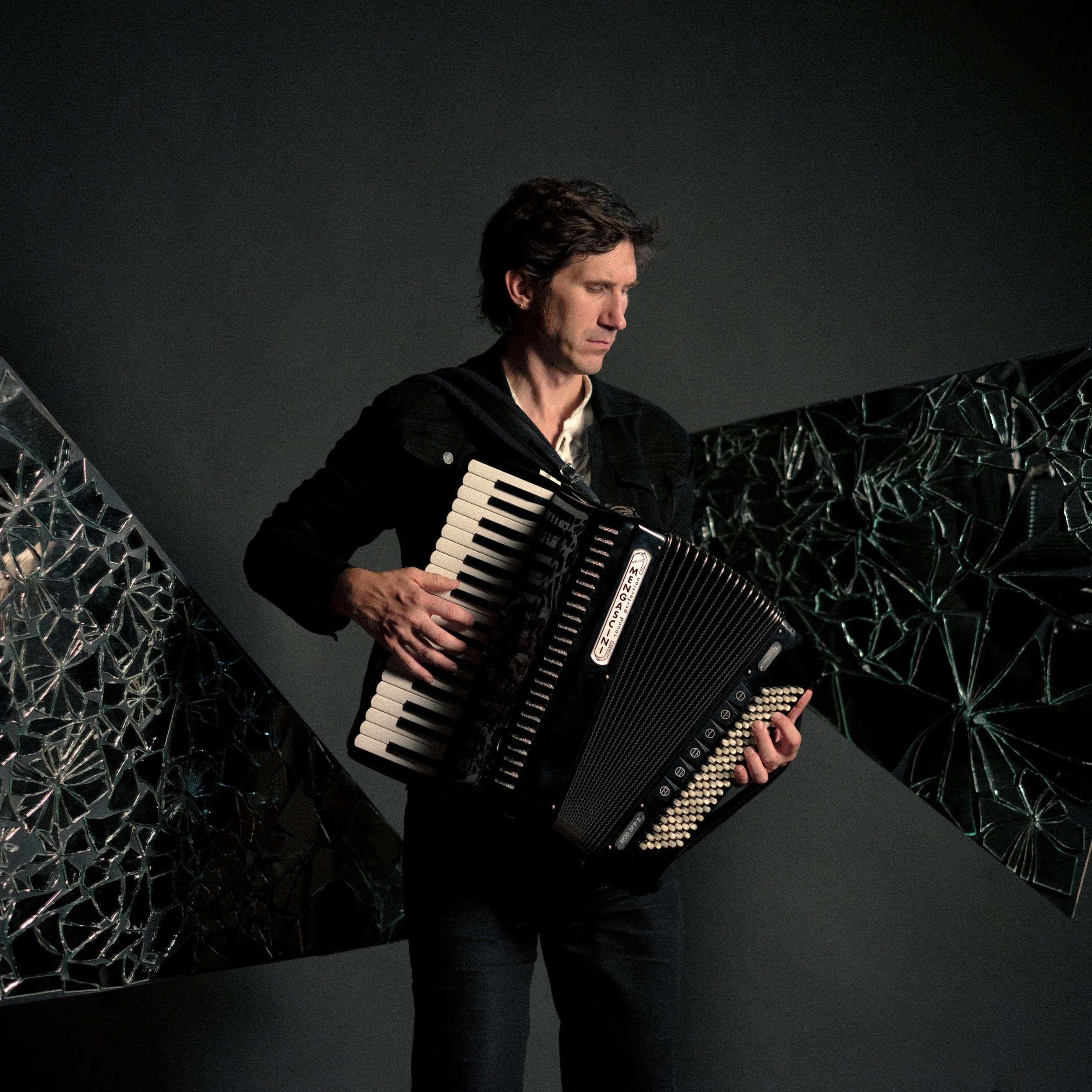 A talented musician plays the accordion in front of a contemporary background with a broken mirror design. An image that unites creativity, musicality, and art in perfect harmony.