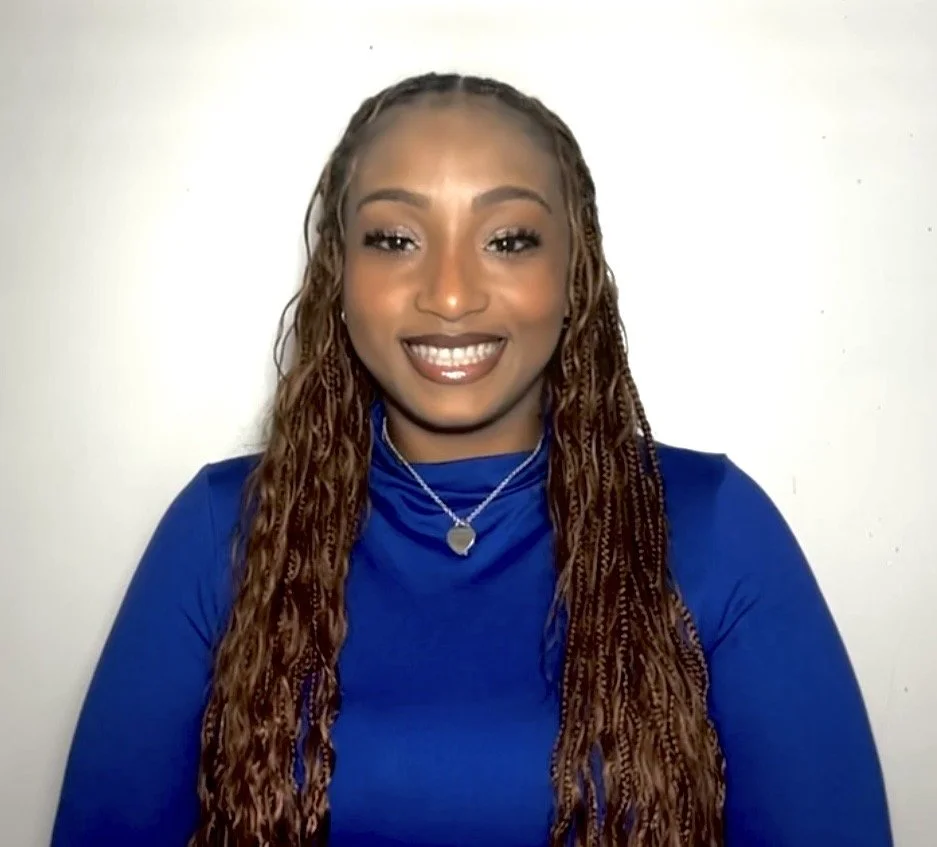 Headshot of Lauryn Ferguson, MHC-LP, therapist at Upstate Counseling, smiling with long braided hair, wearing a blue long-sleeve top and a small heart-shaped necklace against a plain light background.