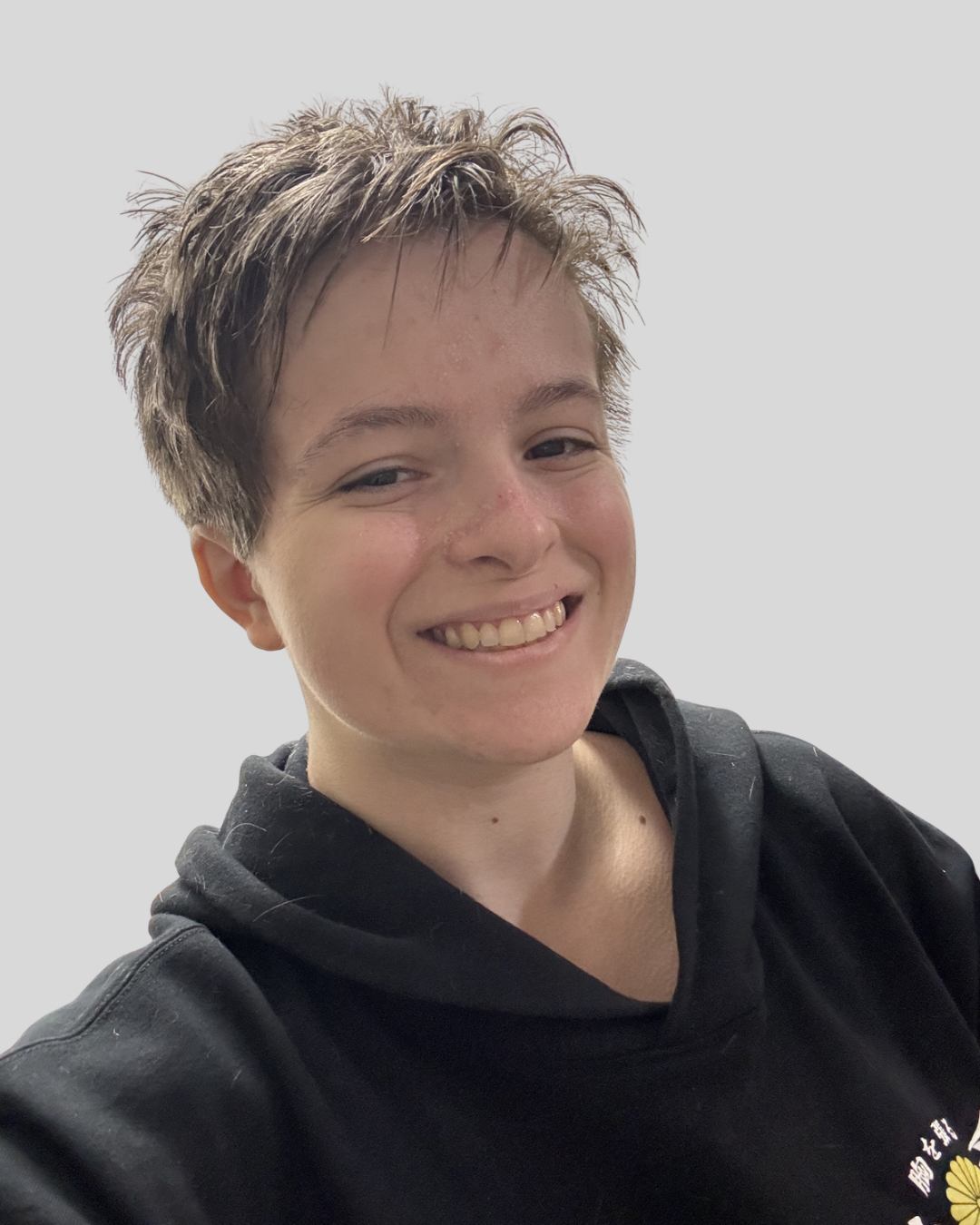 Headshot of Asher Patalano, LMSW, therapist at Upstate Counseling, smiling with short textured hair, wearing a black hoodie against a plain light background.