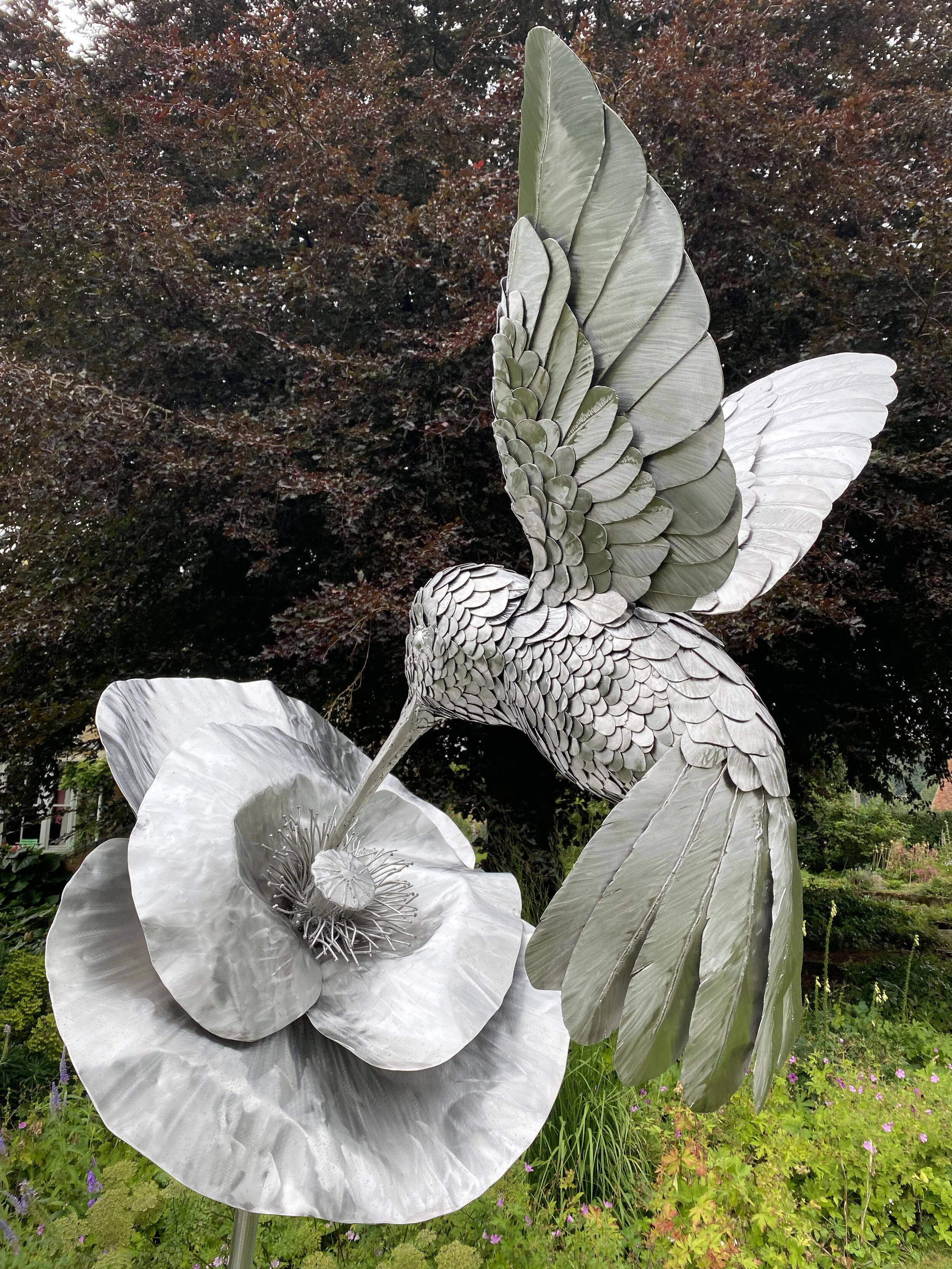  This stunning 9ft-tall hummingbird sculpture, commissioned by a private collector to mark a special wedding anniversary, is crafted from 316 stainless steel. Suspended from a flower by its beak, the hummingbird appears to float gracefully in space, 