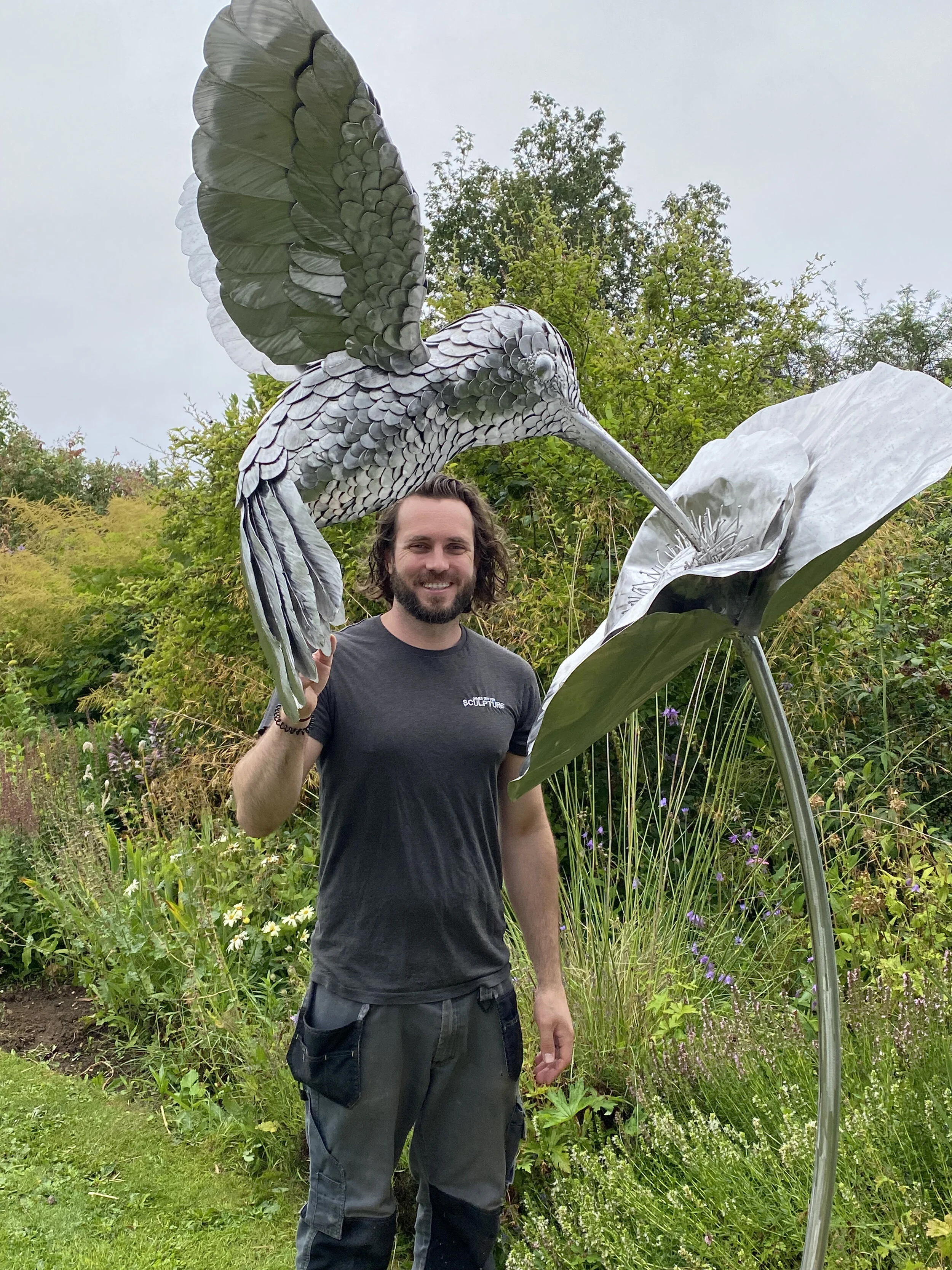 James Sutton stood with his hummingbird sculpture for scale