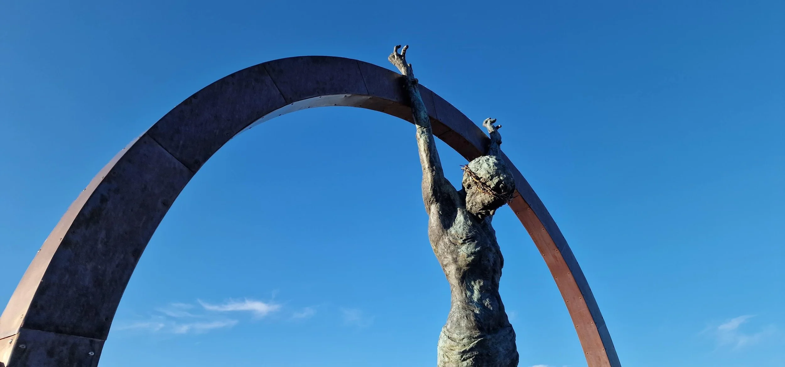  Sacrifice  is a monumental public art installation commissioned for a business on the Isle of Man. Standing at 3 meters tall, the sculpture features a life-sized bronze Christ figure suspended within a frame crafted from stainless steel and copper.