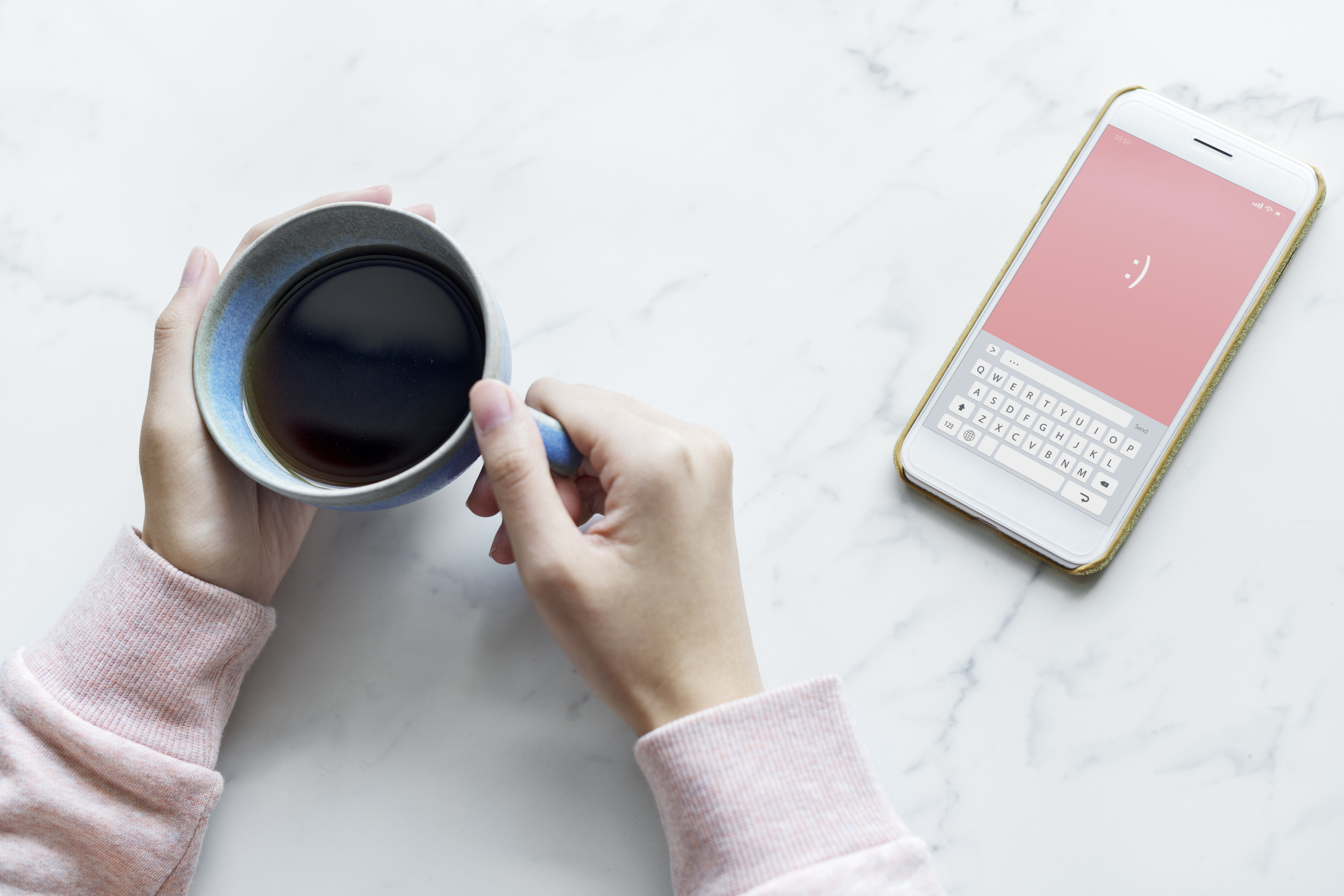 Aerial view of woman with a hot cup of coffee and a smartphone