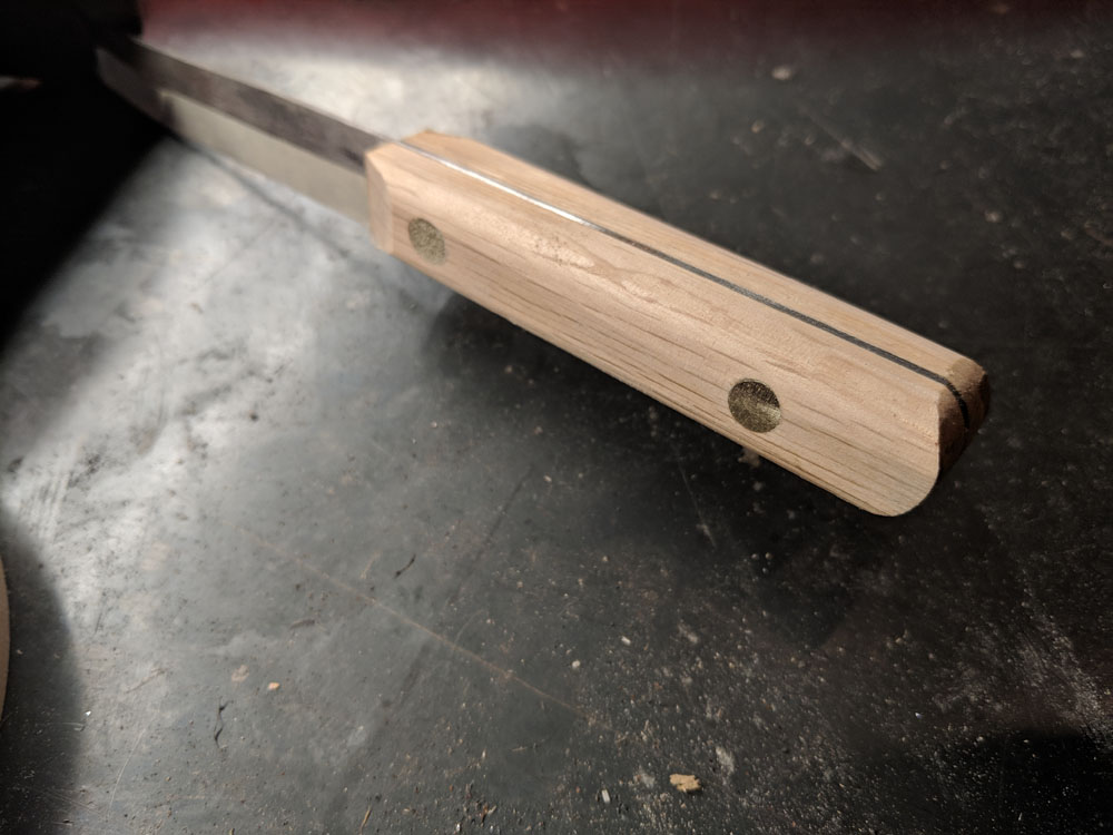  At this point I could begin shaping the handle. I started by sanding off any excess material so that the wood would be flush with the tang. Then I sanded the pins flush with the wood. Finally I began shaping the handle. 