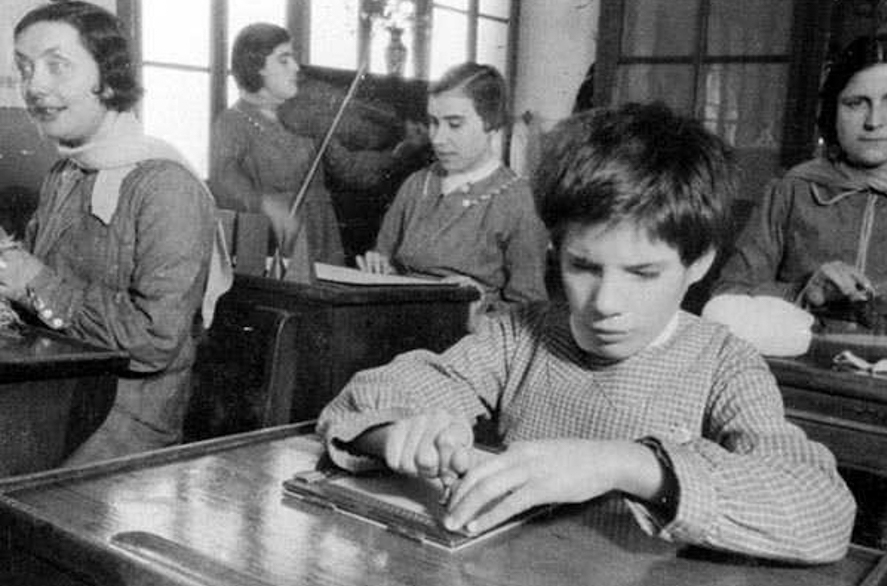 Jóvenes invidentes leyendo mapas en relieve y lectura en Braille en un Centro Asistencial para ciegos en plena guerra civil. 1936-1937