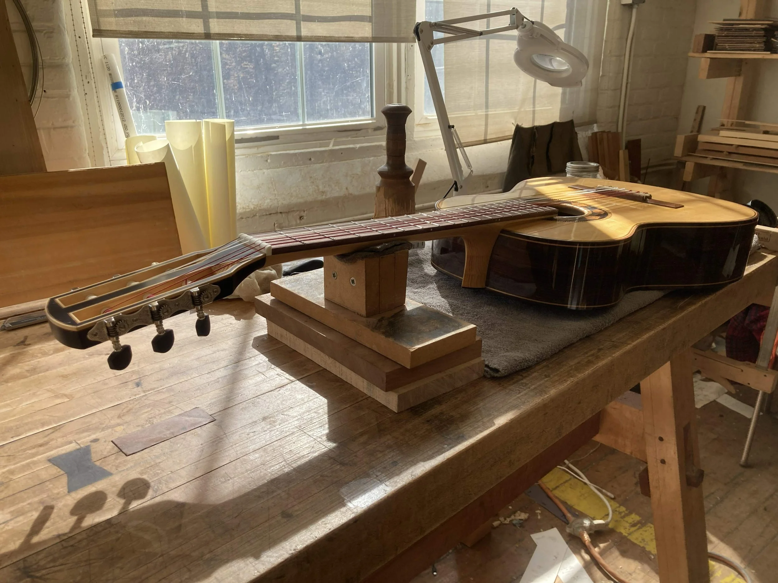 A Queen City Guitars classical lies in repose on the workbench in luthier Aaron Foster's shop in the Cotton Mill building in Brattleboro Vermont.