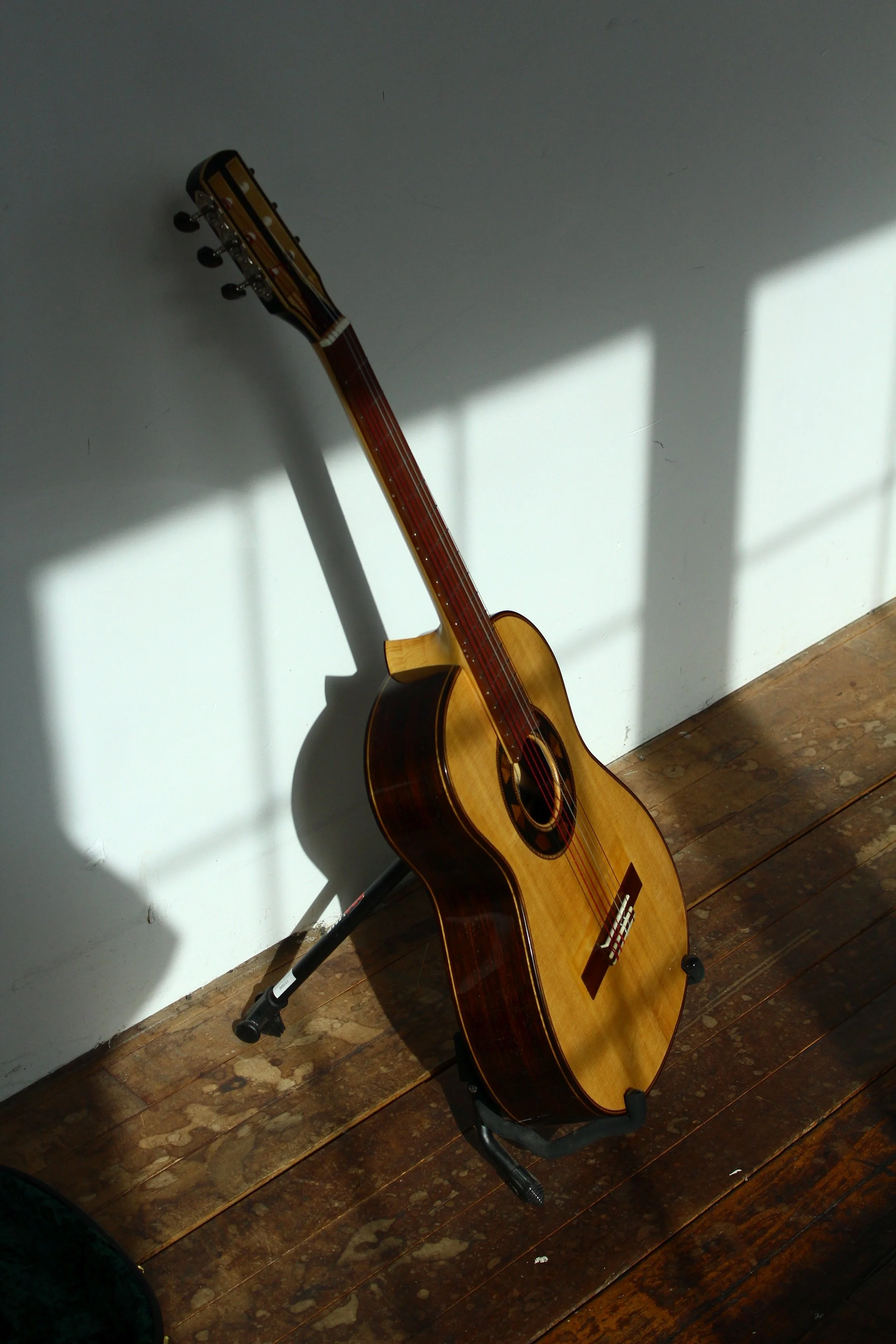 rosewood and spruce classical with an alaskan yellow cedar neck looking moody in the sunset outside of the shop of Brattleboro Vermont custom guitar shop, queen city guitars