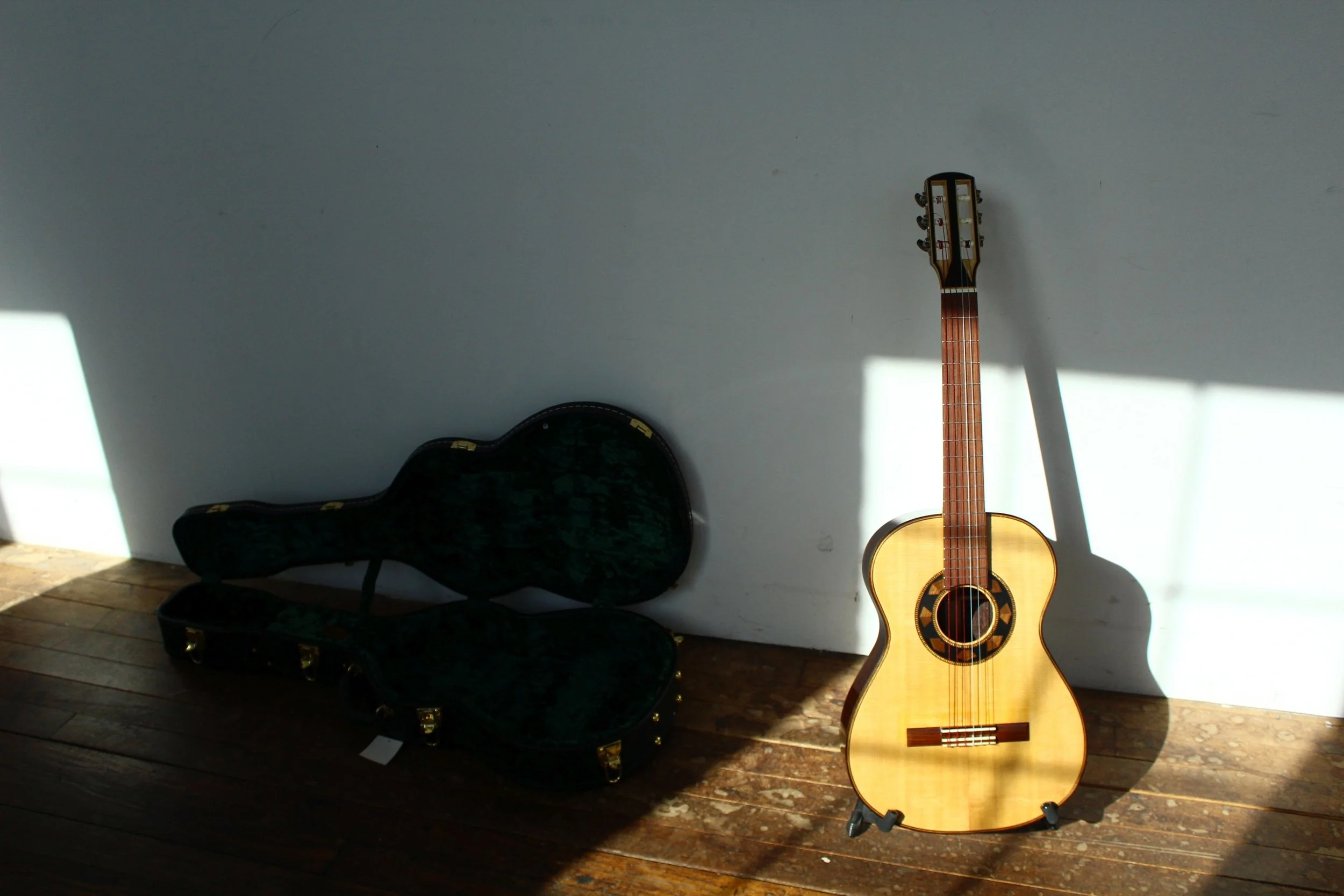 Afternoon sun shines in the south windows of the historic cotton mill building in Brattleboro Vermont, illuminating the top, rosette and neck of a classical guitar built by Aaron Foster in the Queen City Guitars shop