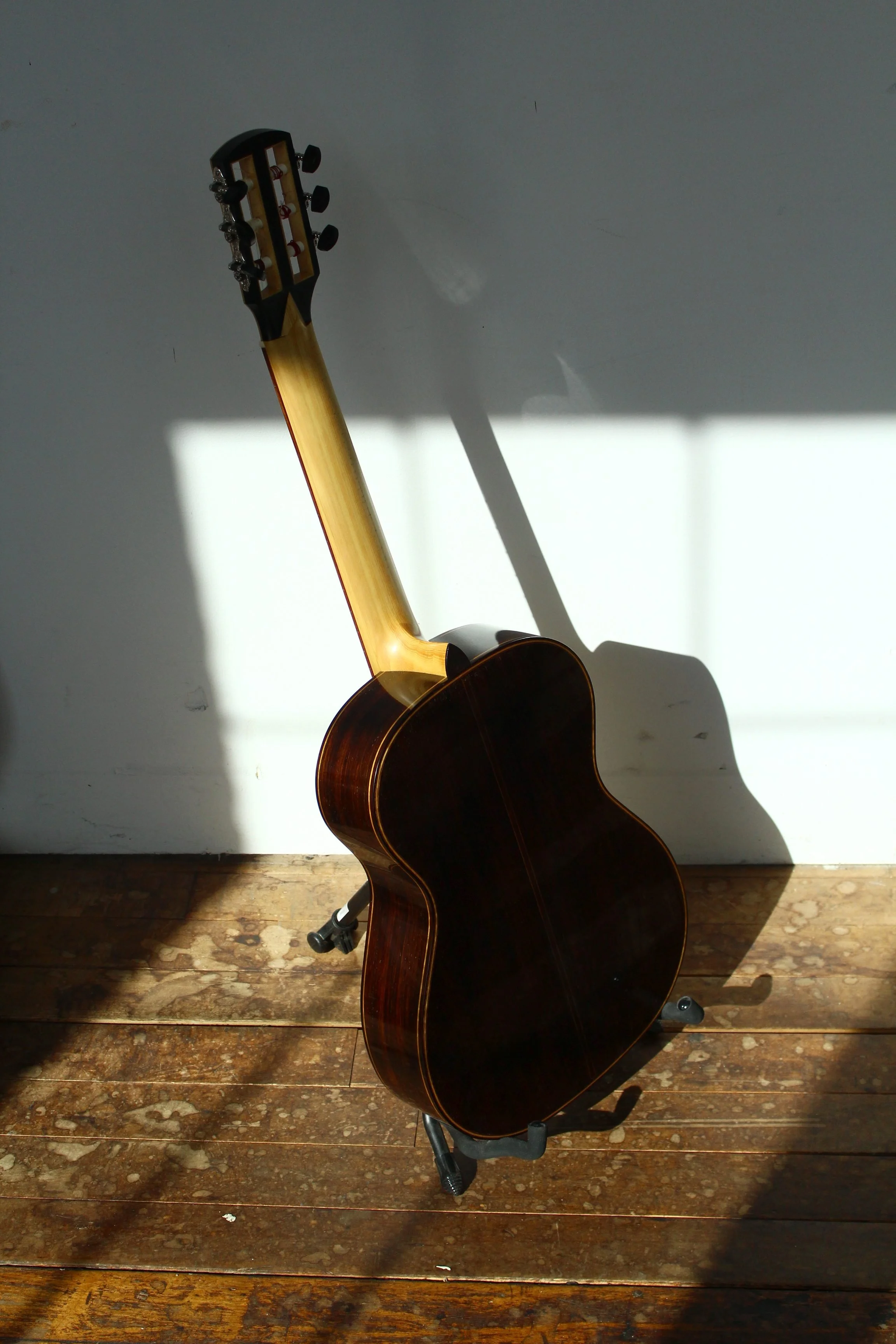 Seen from the back the rosewood of this classical guitar contrasts with the curly myrtle purfling and Alaskan yellow cedar neck in the Vermont sun at the historic Cotton Mill building in Brattleboro Vermont.